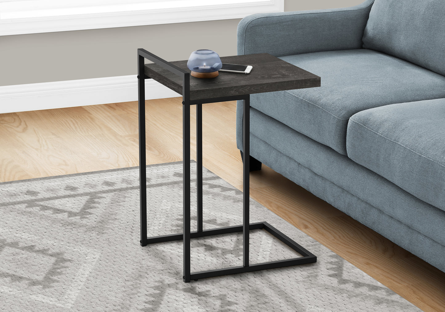 Dark wood and black metal Ctable placed next to blue sofa for modern living room accent