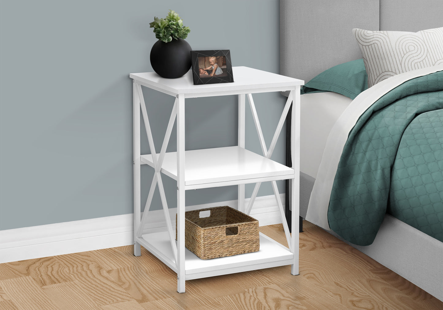 White Xframe end table with two shelves holding a woven basket and decorative items
