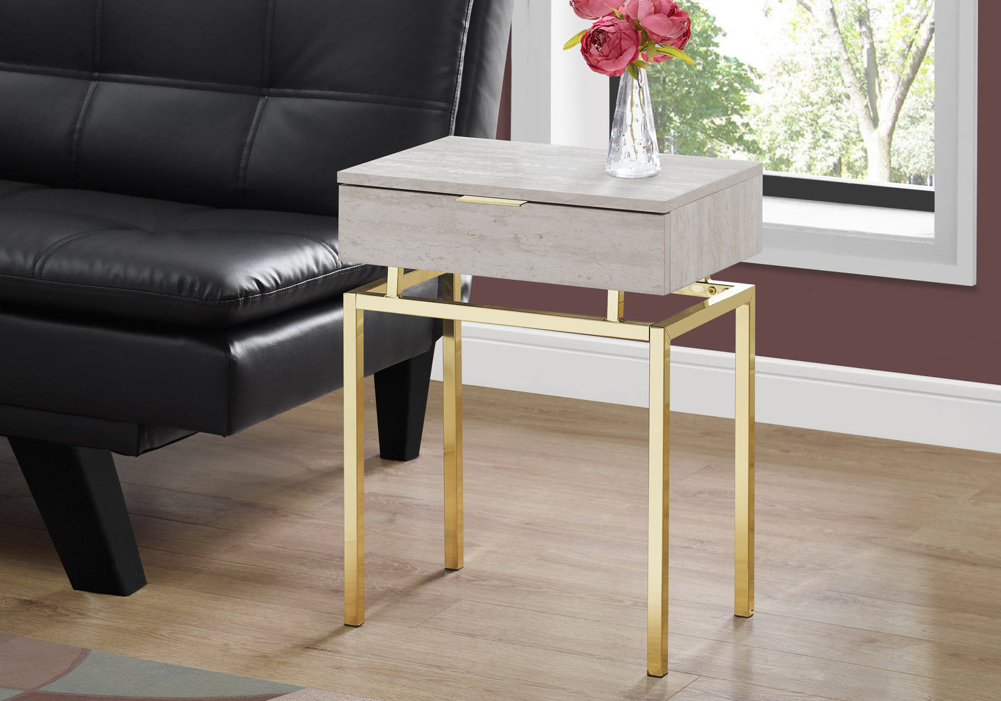 Modern grey stone accent table with gold metal legs next to black sofa