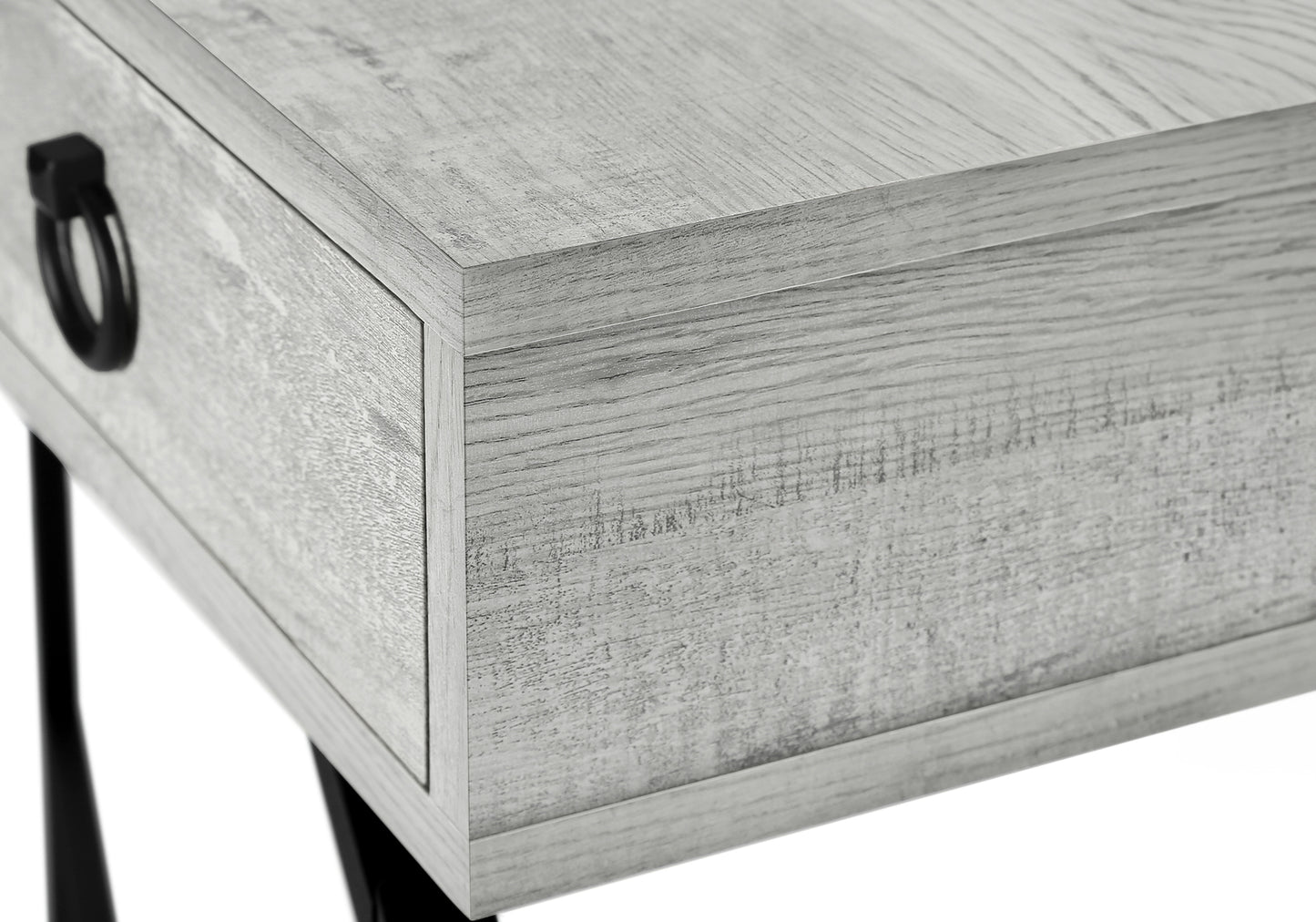 Close up of a grey weathered wood bedside table with a black ring pull drawer handle