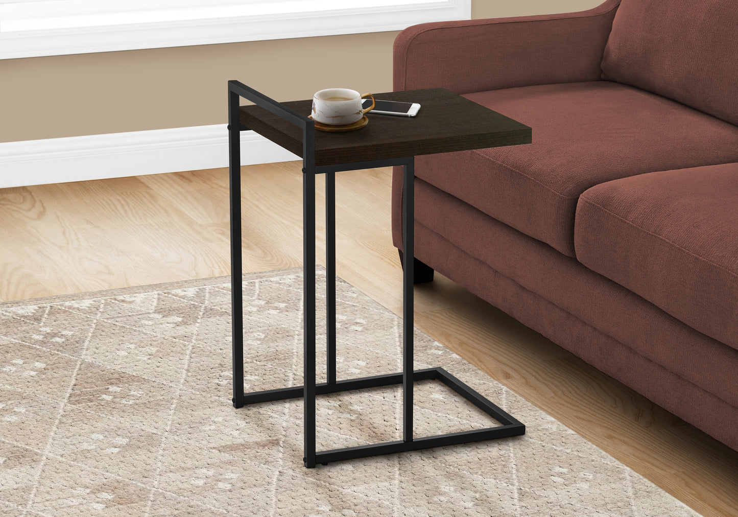 Dark wood ctable with black metal frame holding a mug and phone