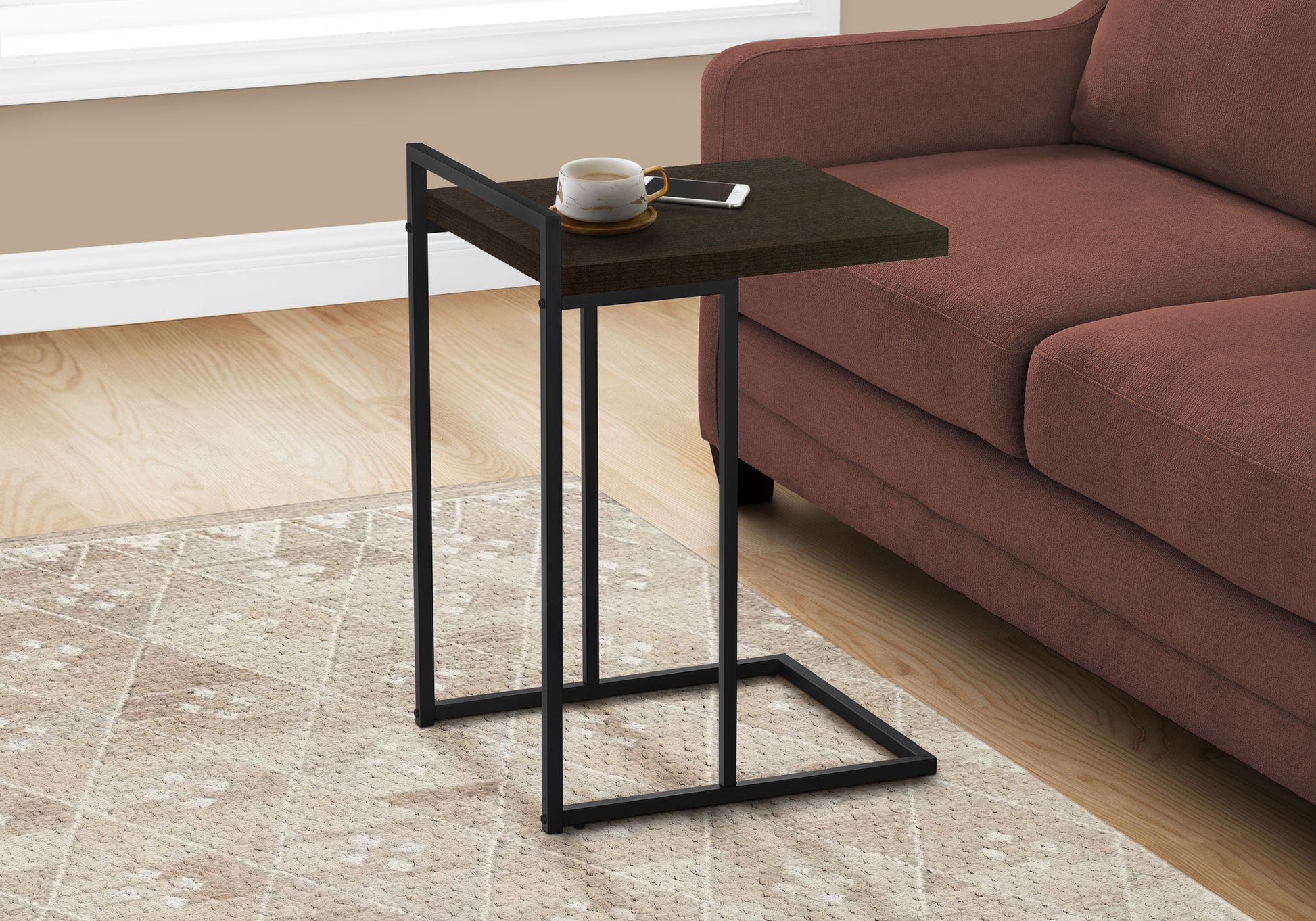 Dark wood ctable with black metal frame holding a mug and phone
