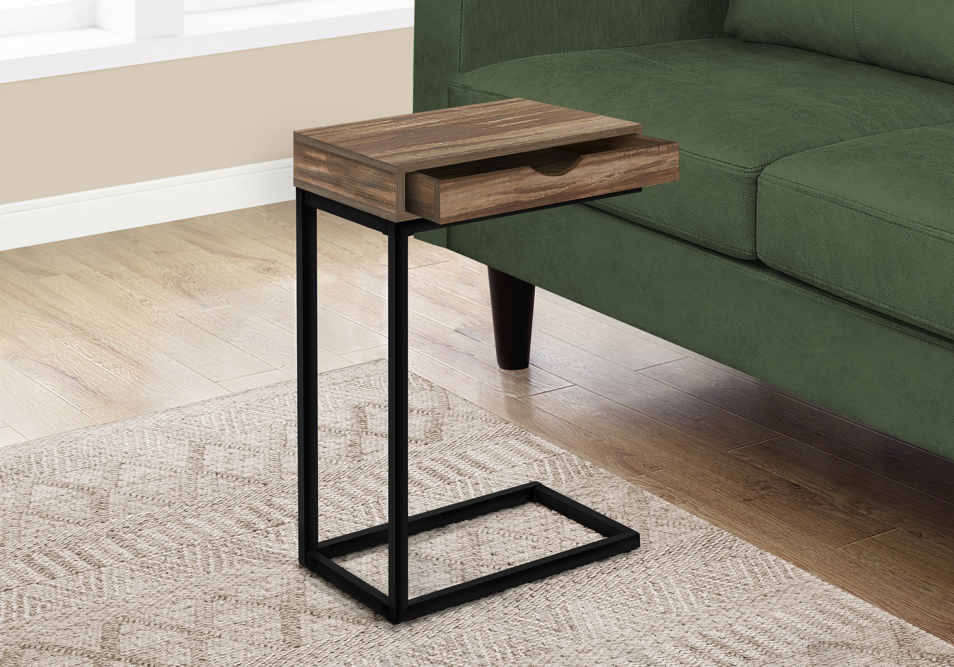 Wood effect ctable with black metal frame and open drawer beside a green couch