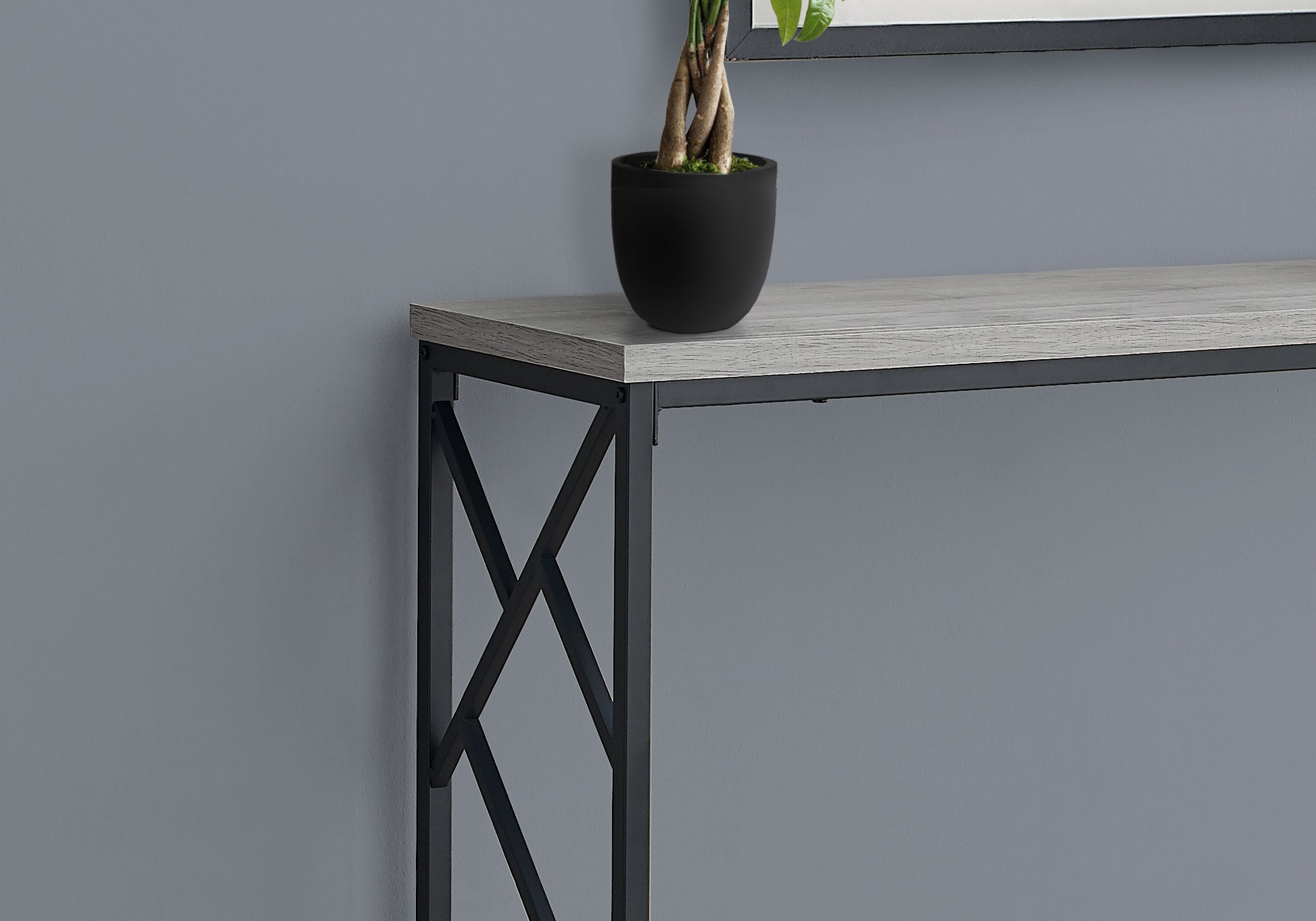 Grey washed wood console table with black metal legs and geometric accents