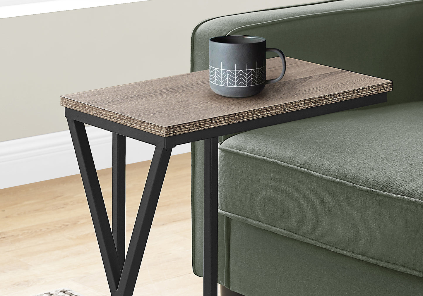 Wood grain Ctable with black metal frame resting on green sofa