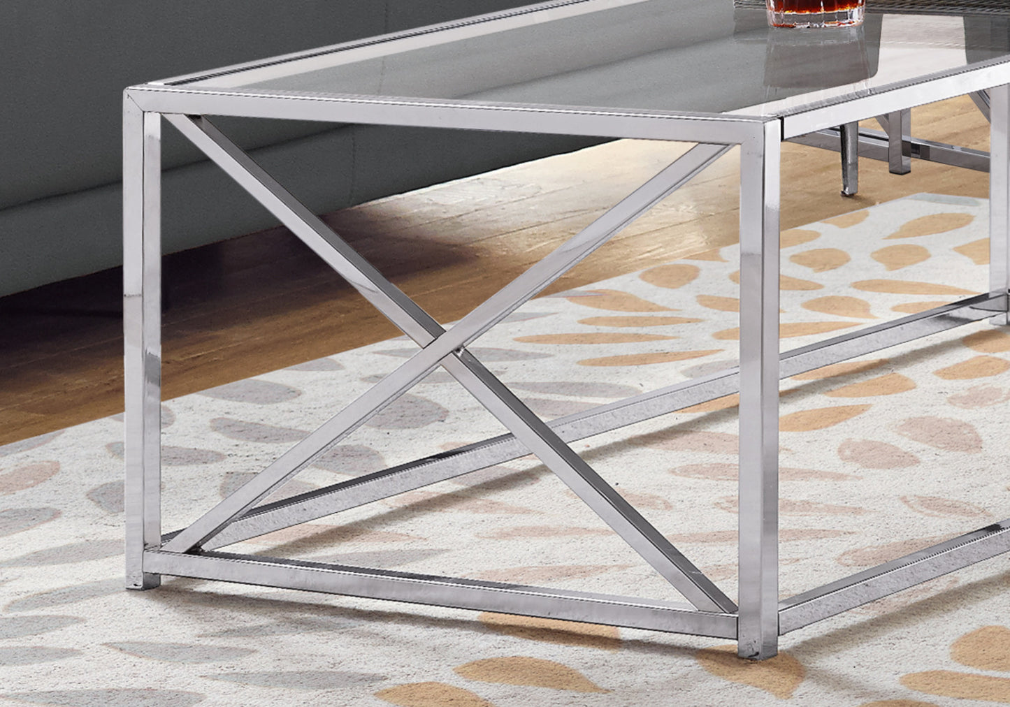 Modern chrome coffee table with a glass top and Xframe legs