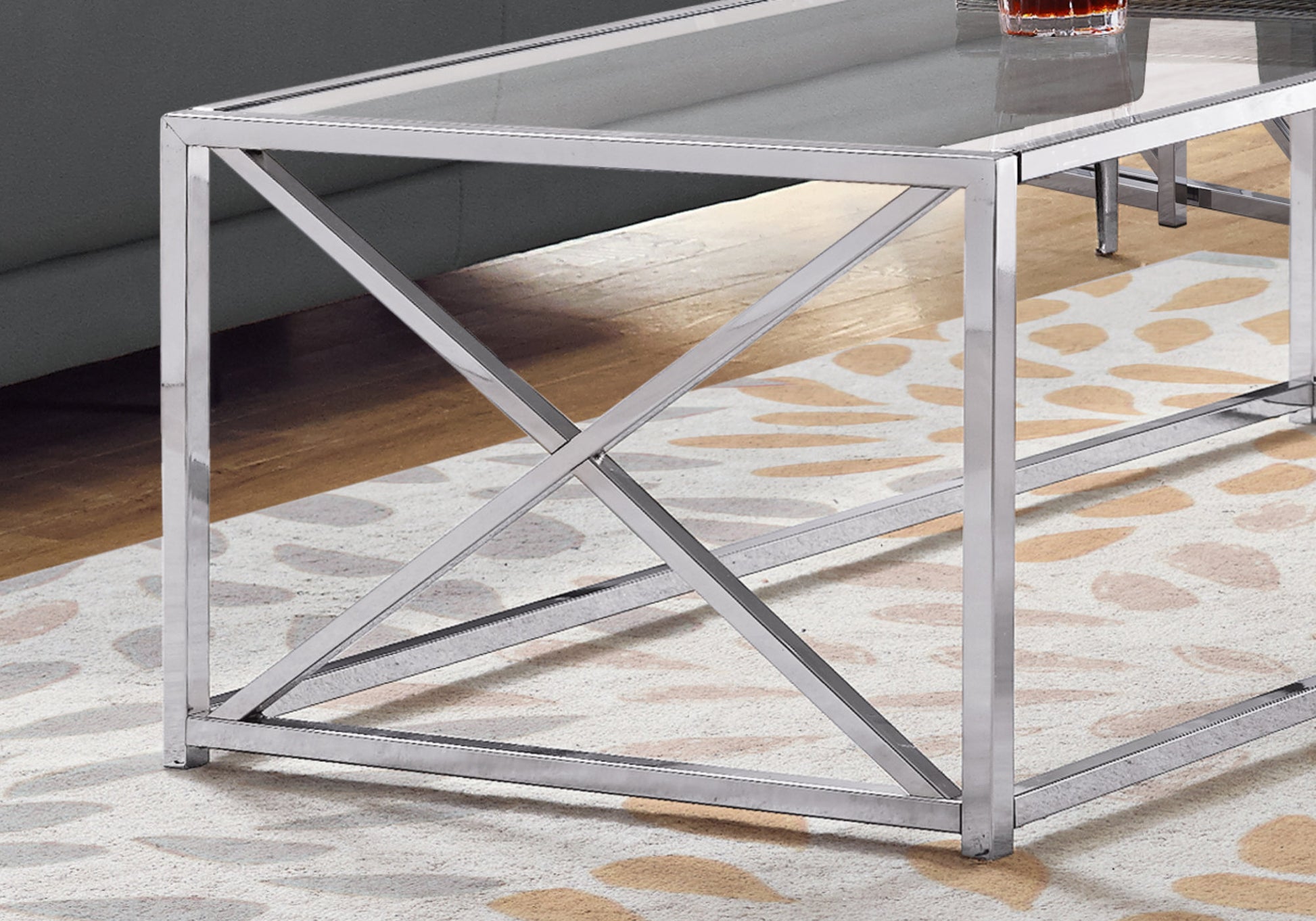 Modern chrome coffee table with a glass top and Xframe legs