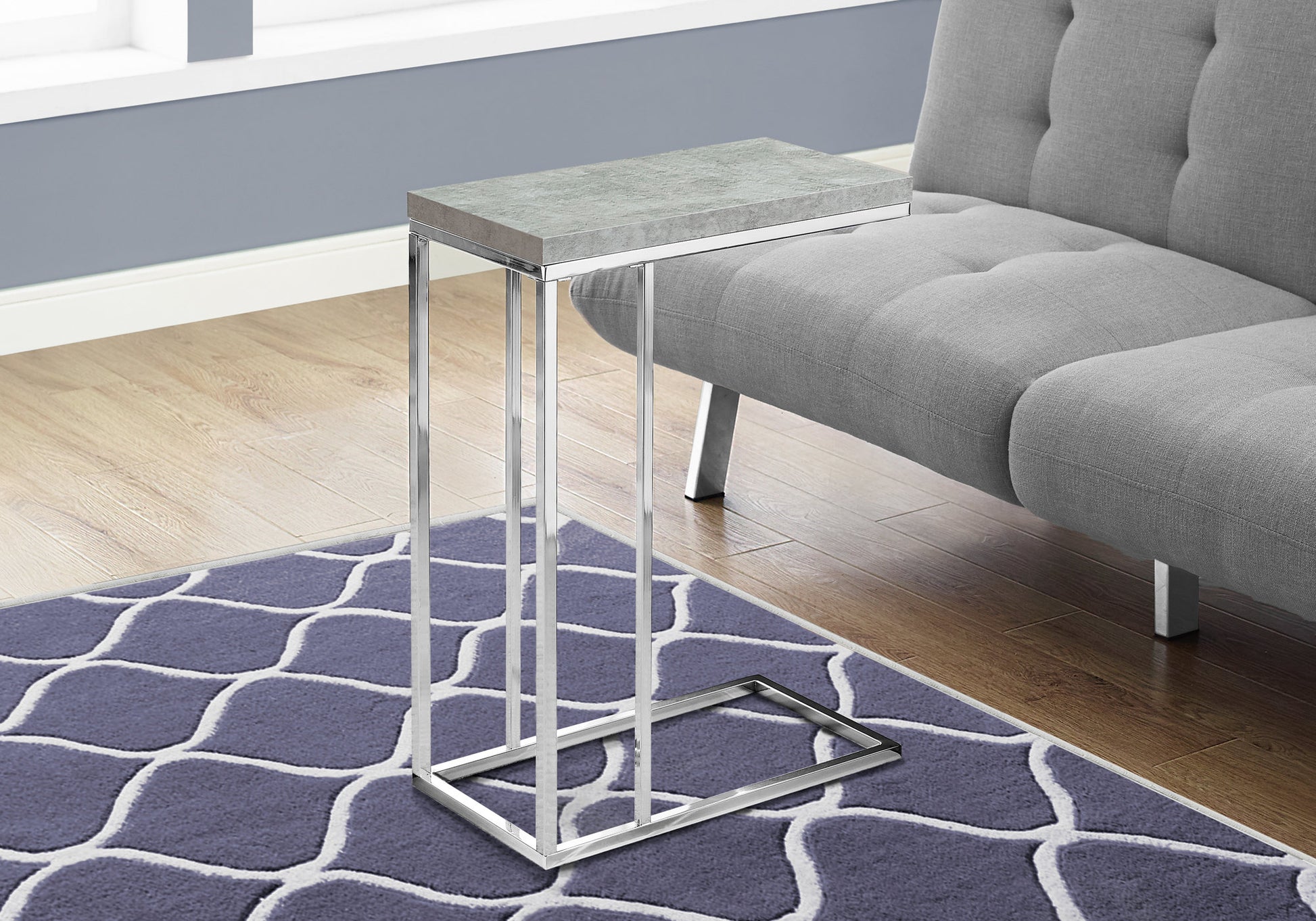 Modern grey concrete top ctable with polished chrome base beside grey sofa