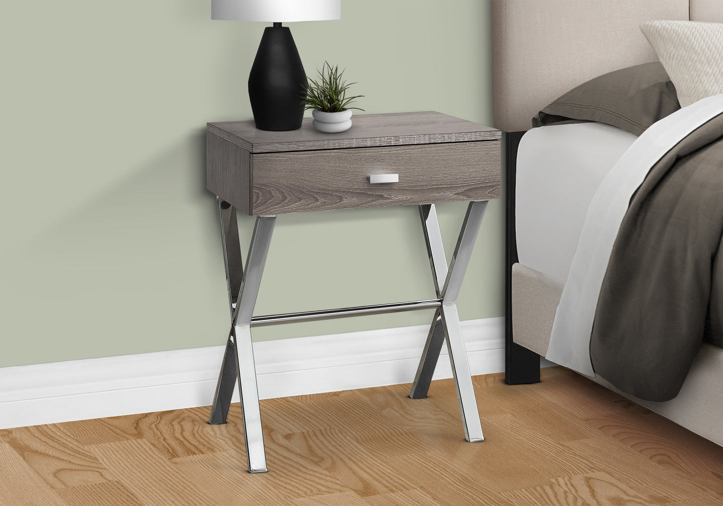 Grey wood nightstand with chrome Xlegs and one drawer beside a bed