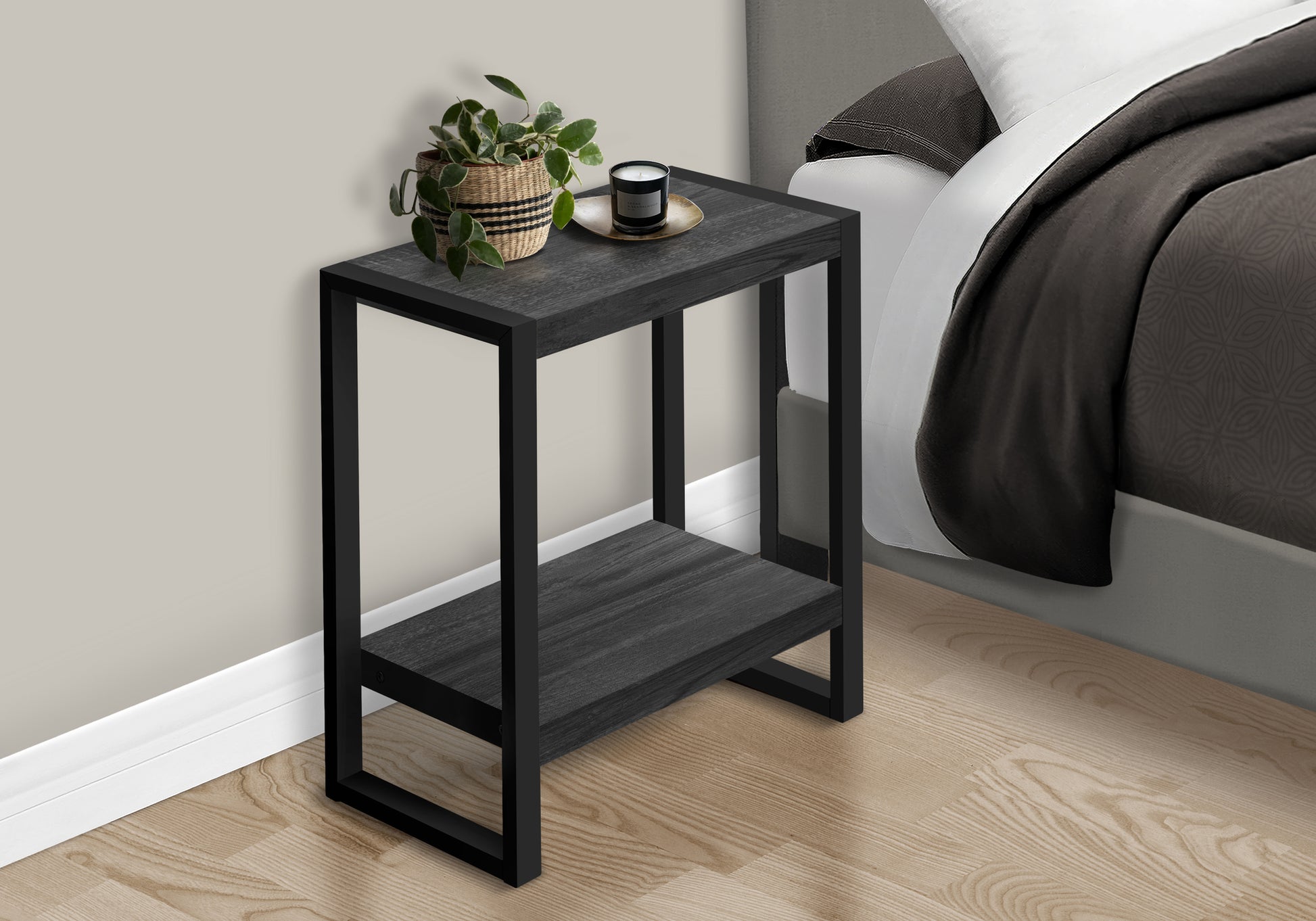 Modern black metal side table with dark wood grain shelves next to a bed