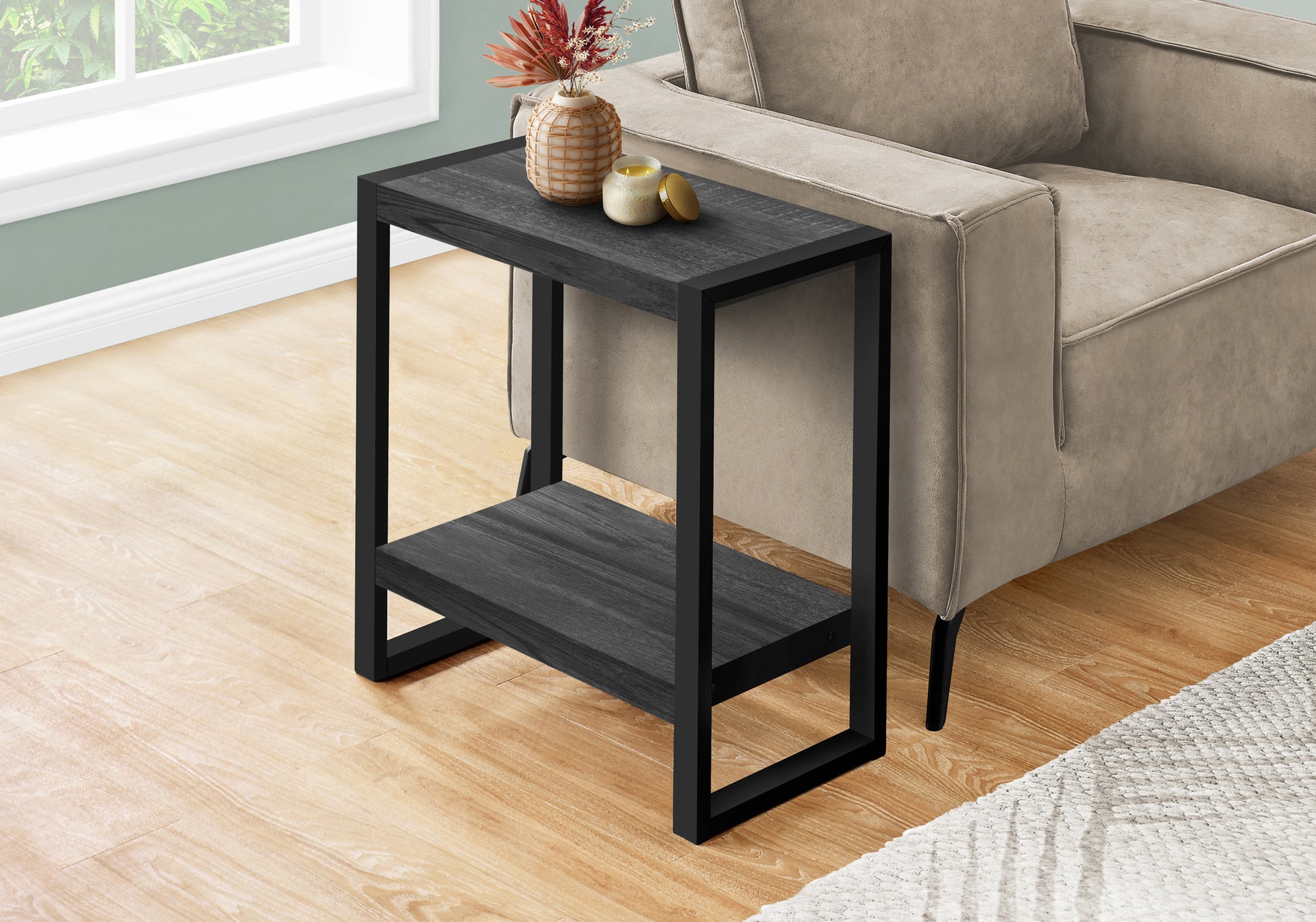 Black wood grain and metal end table with two shelves beside a sofa