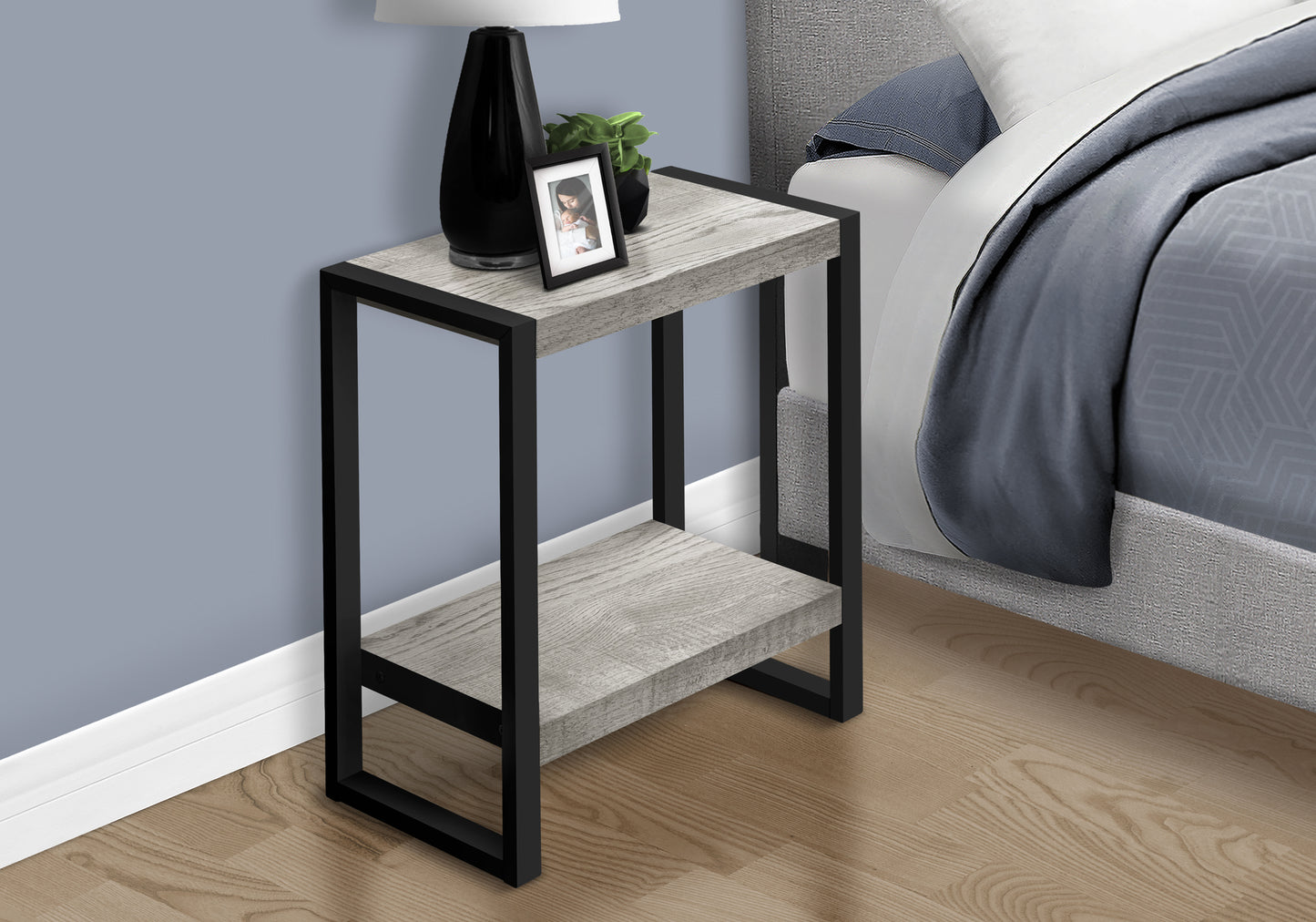 Modern gray wood and black metal end table with two shelves next to a bed