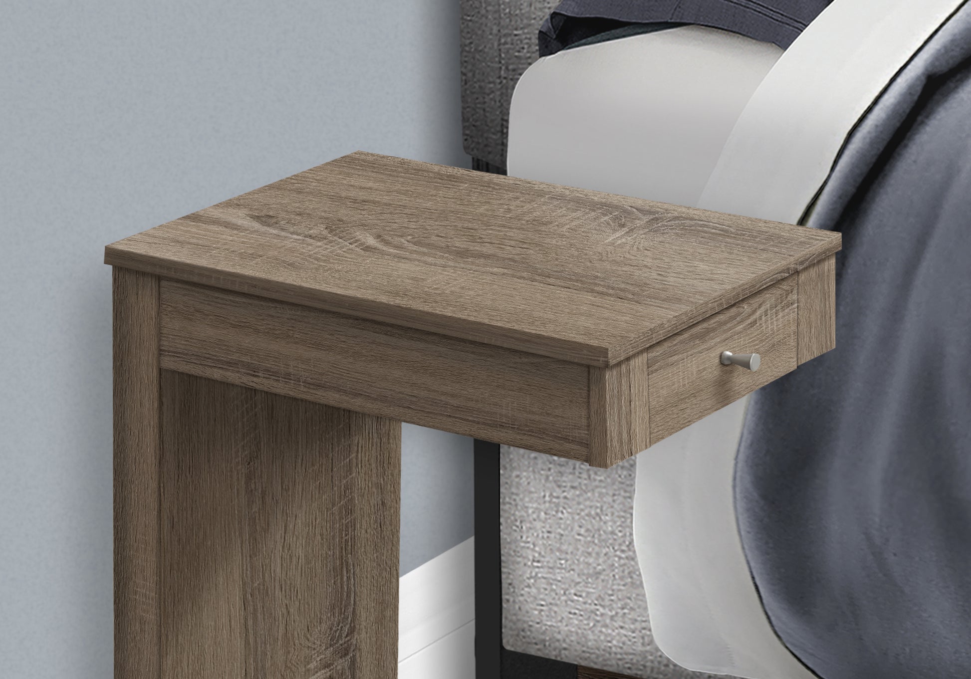 Rustic oak finish bedside table with one drawer next to a bed