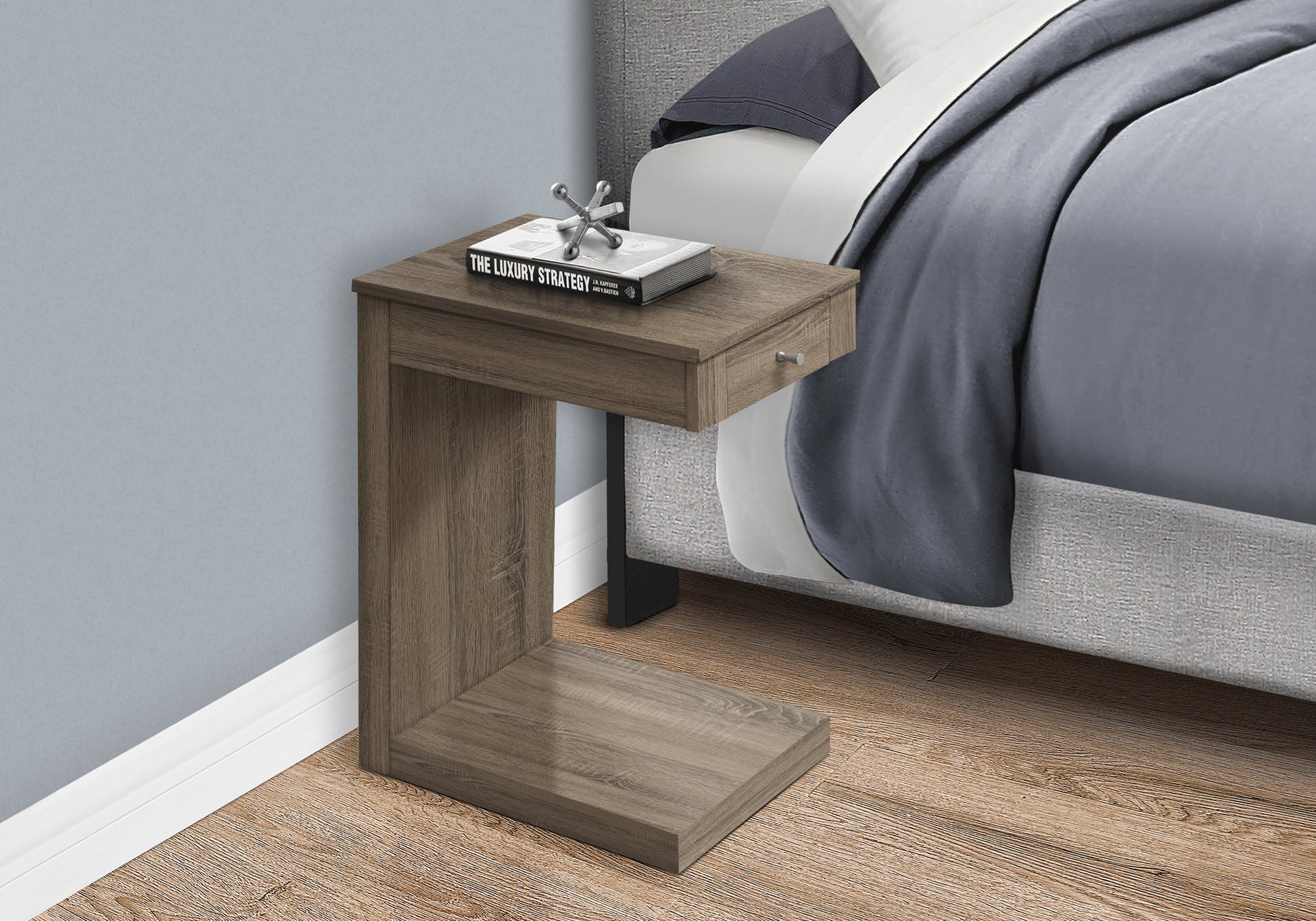 A modern Cshaped side table in weathered oak finish perfect for next to a bed