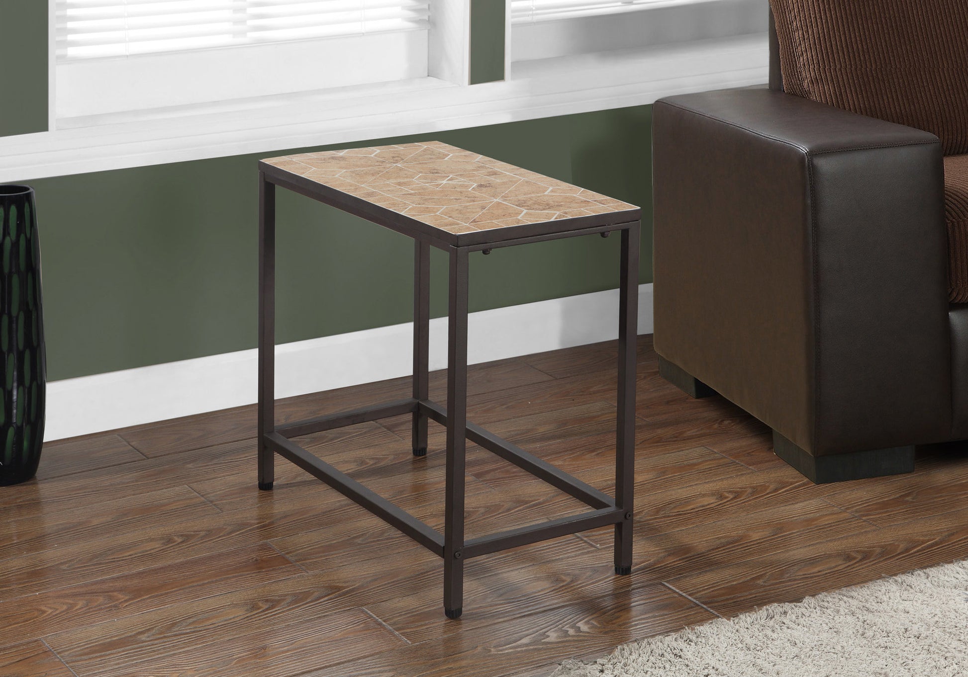 A slender metal end table with a geometric tiled top sits next to a brown leather sofa