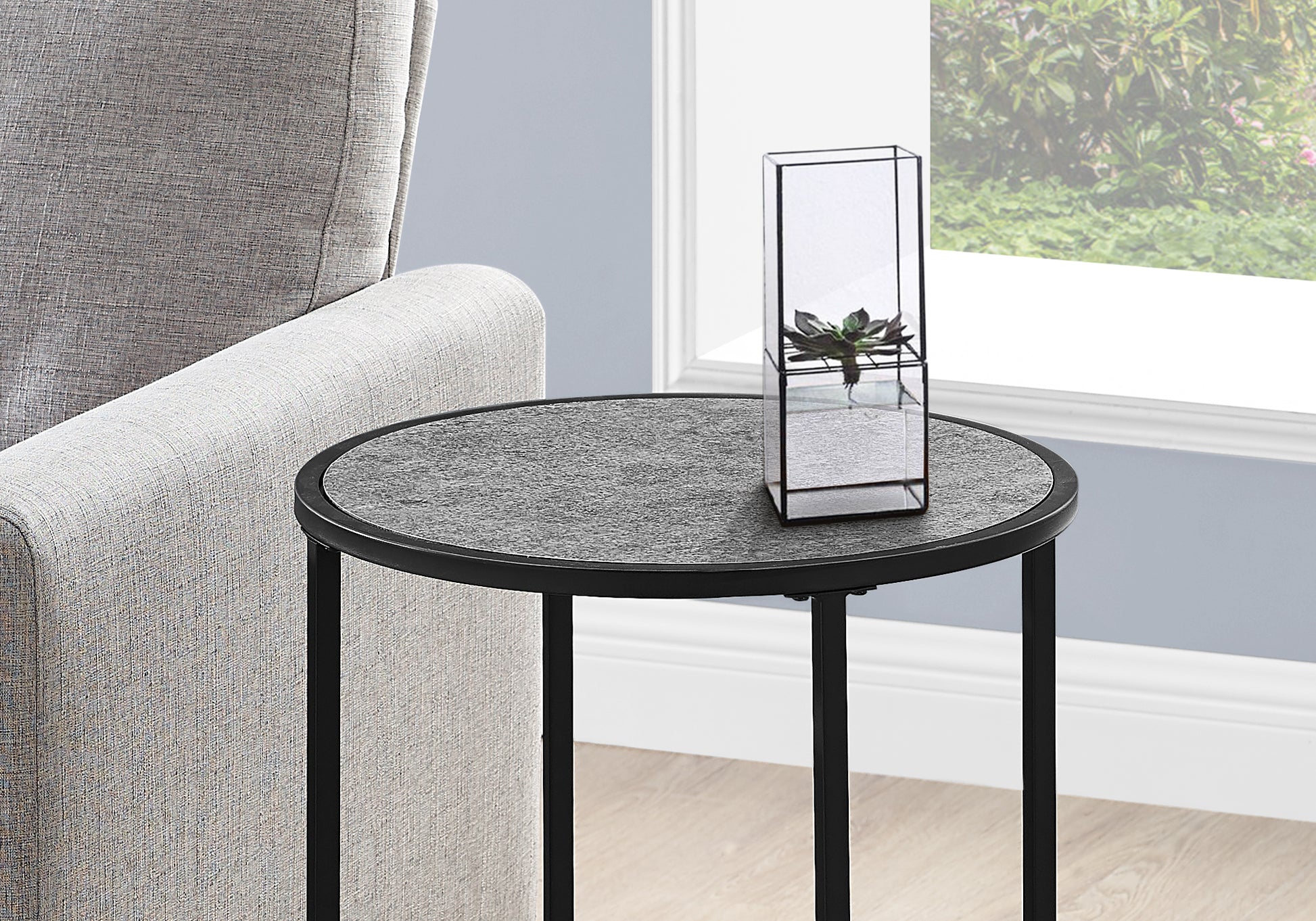 Round stone top side table with black metal legs and a geometric terrarium