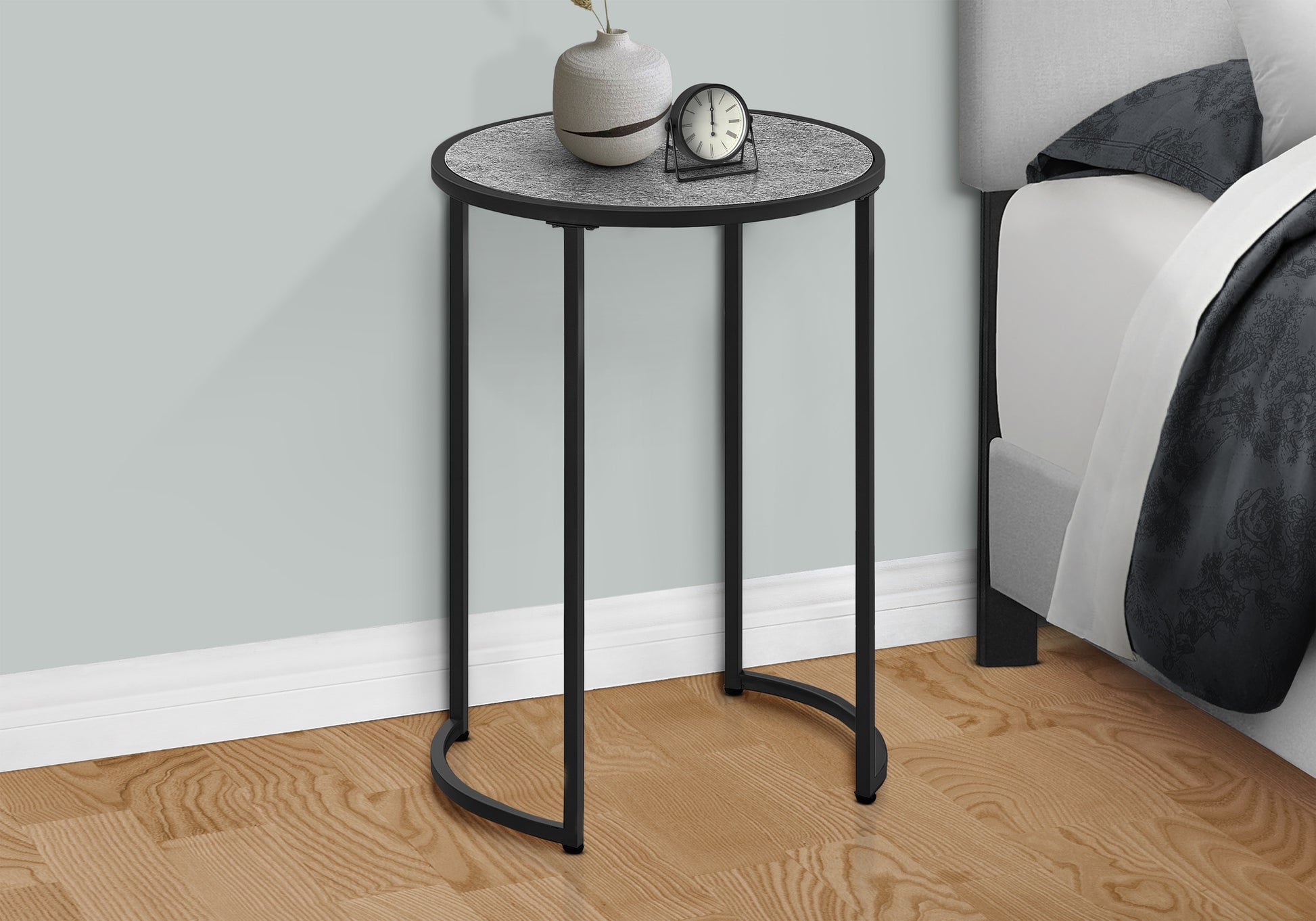Round metal end table with speckled grey top and black curved legs