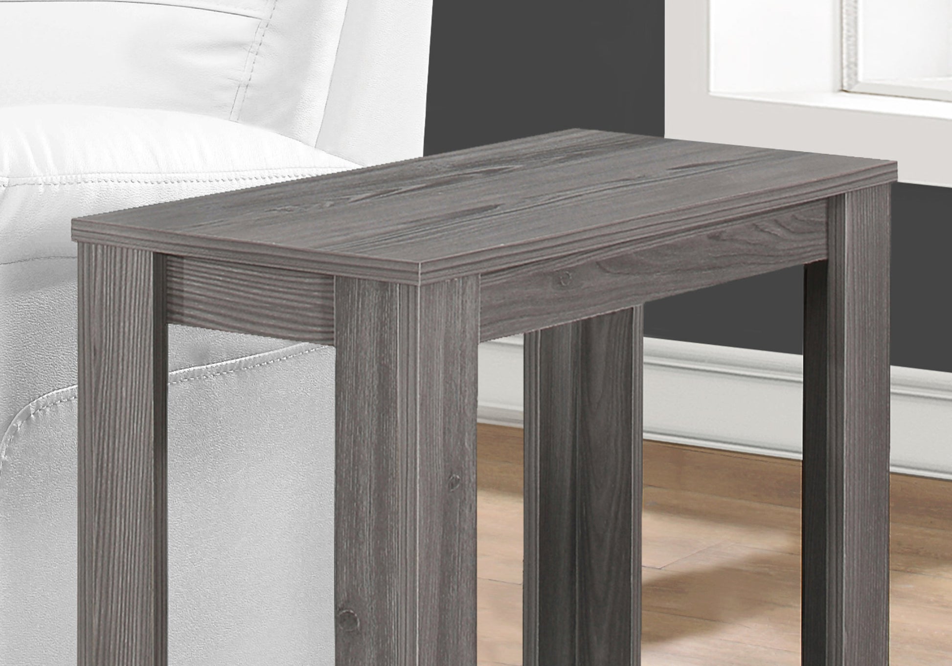 Narrow gray wood accent table with sleek design next to white armchair
