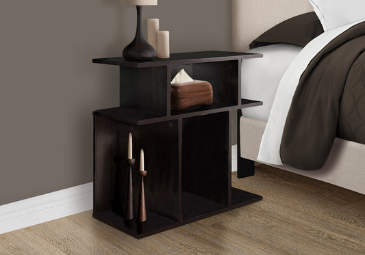 Dark wood end table with open shelves beside a bed holding a lamp and tissue box