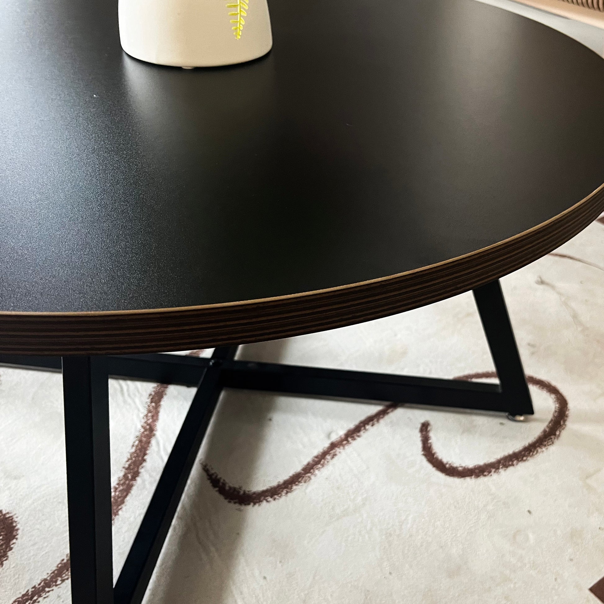 Black round coffee table with a modern geometric metal base perfect for living rooms