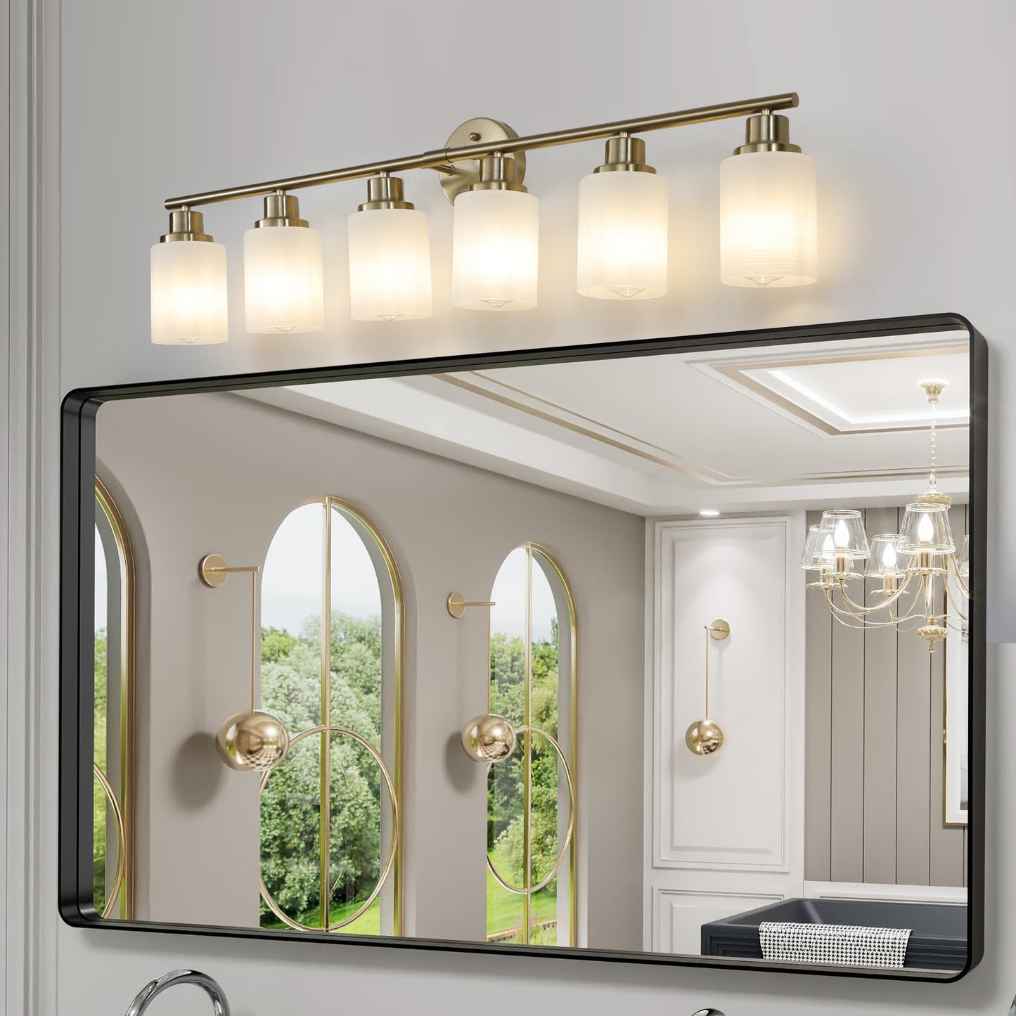 Modern brass vanity light fixture with five frosted glass shades above a black framed mirror