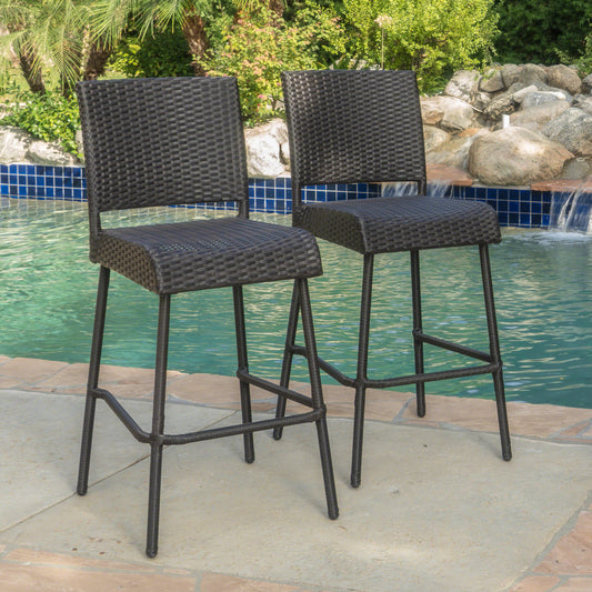 Two dark brown wicker bar stools with metal frames positioned by a swimming pool