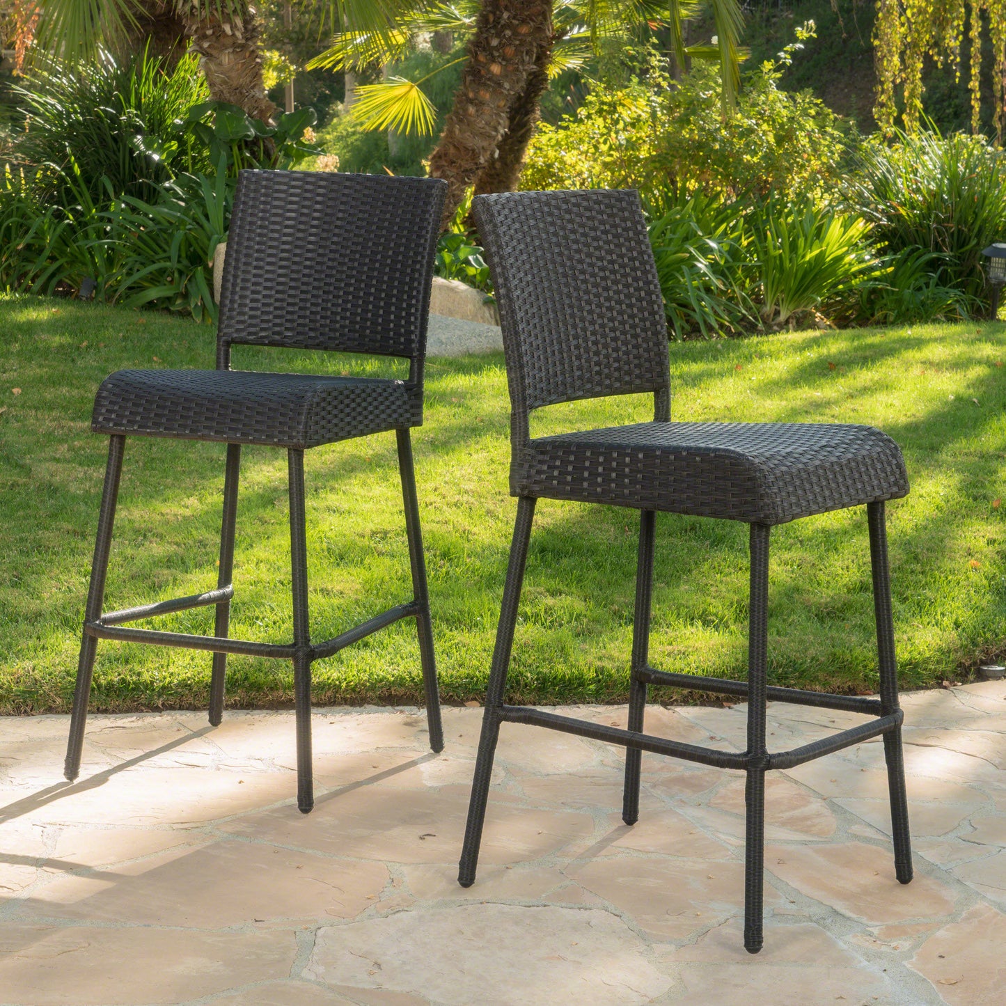 Two dark brown wicker bar stools on a stone patio perfect for outdoor entertaining
