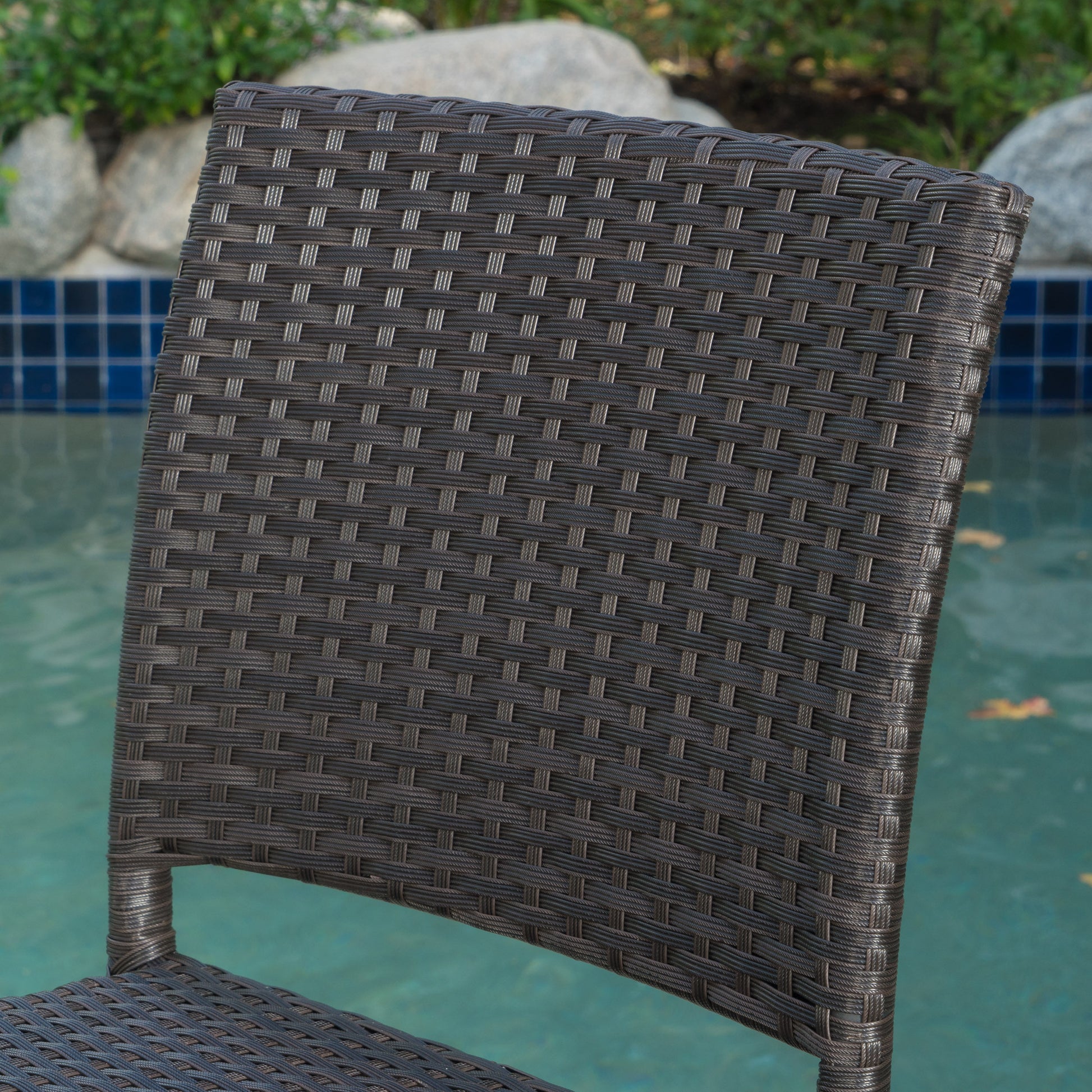 Dark brown wicker patio chair back with intricate weave pattern