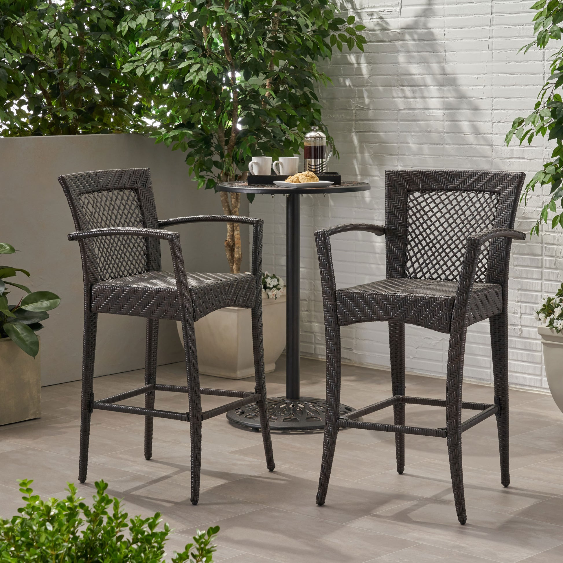 Dark brown wicker bar stools with armrests and footrests for outdoor patios