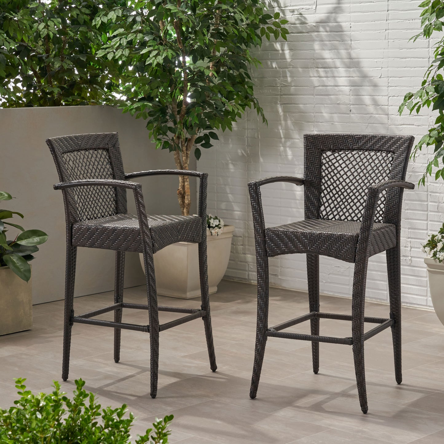 Two dark brown wicker bar stools with intricate woven patterns on a tiled patio