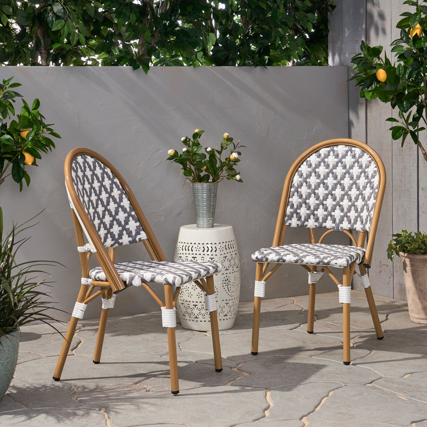 Pair of rattan bistro chairs with grey and white geometric seat pattern
