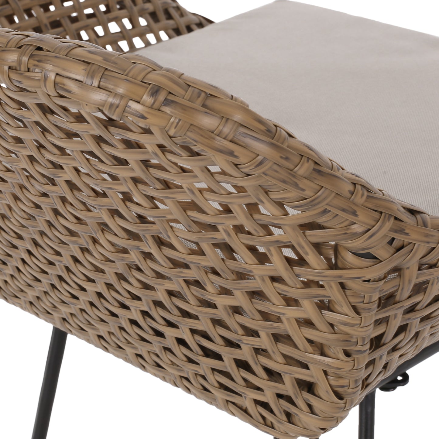 Closeup of tan wicker armchair with textured light gray cushion outdoor patio furniture