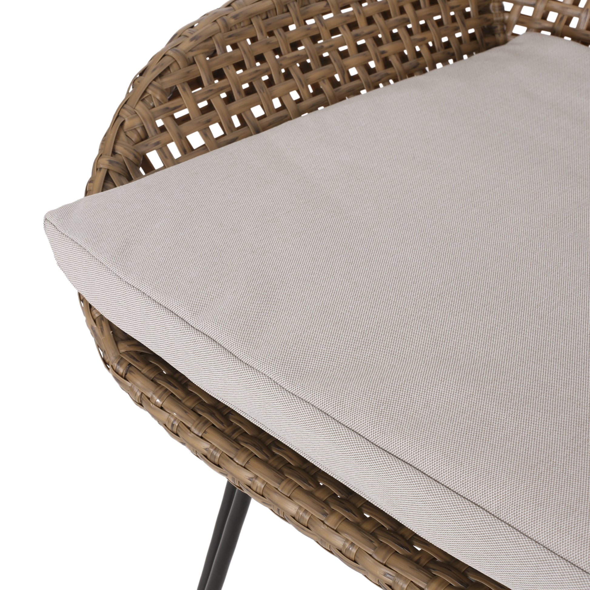 Closeup of a brown wicker chair with a beige seat cushion