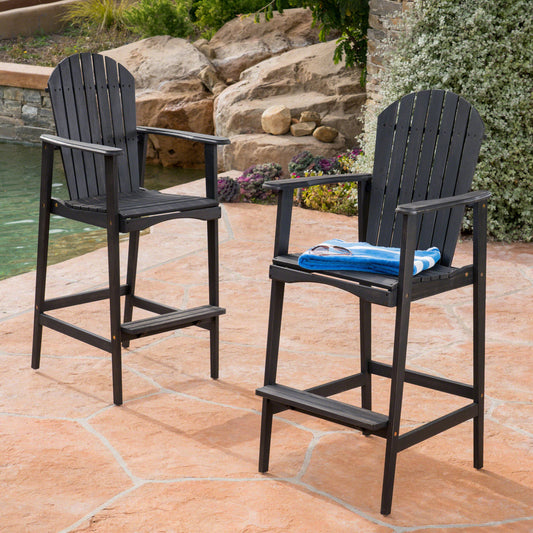Two dark brown wooden Adirondack bar stools with a blue towel on one seat