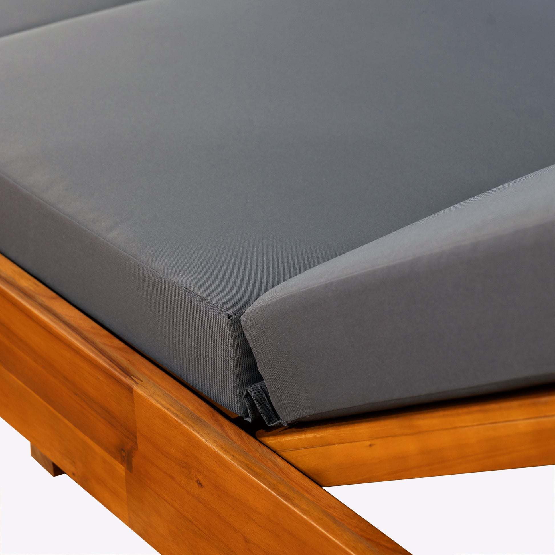 Closeup of a plush grey cushion on a wooden lounger with rich grain detail