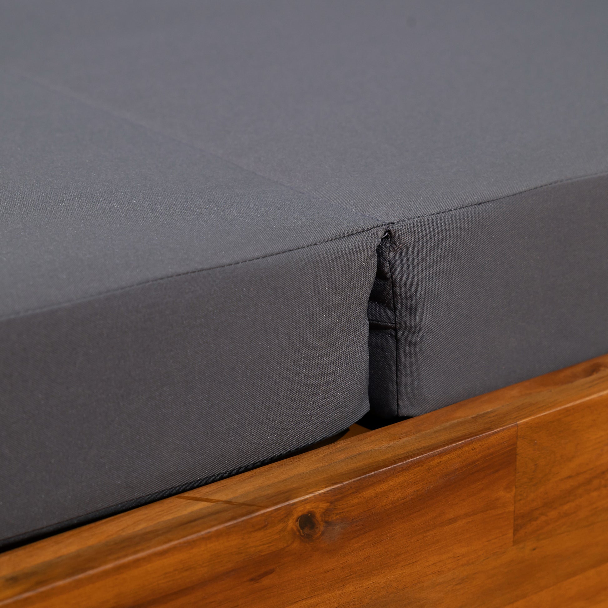 Closeup of charcoal gray outdoor cushion fabric on a wooden frame