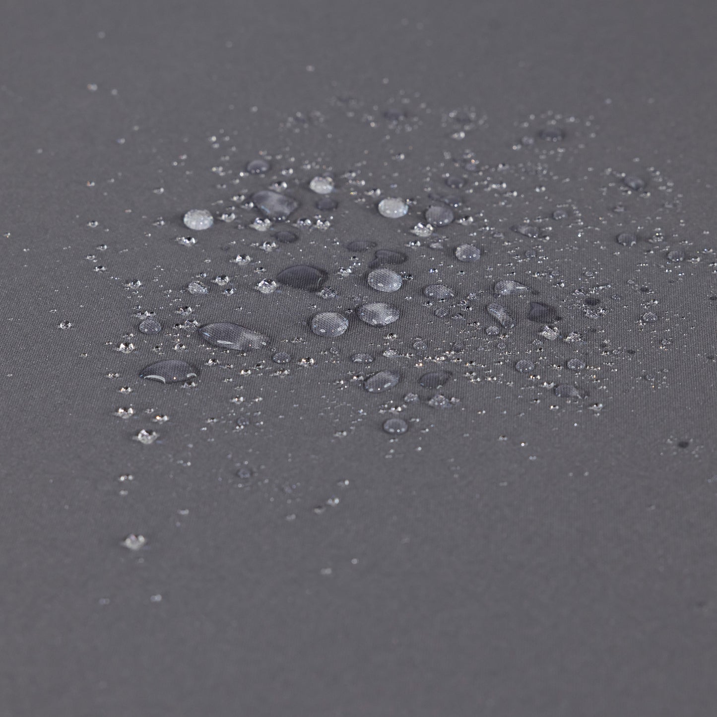 Closeup of dark grey fabric showing water beads on its waterproof surface