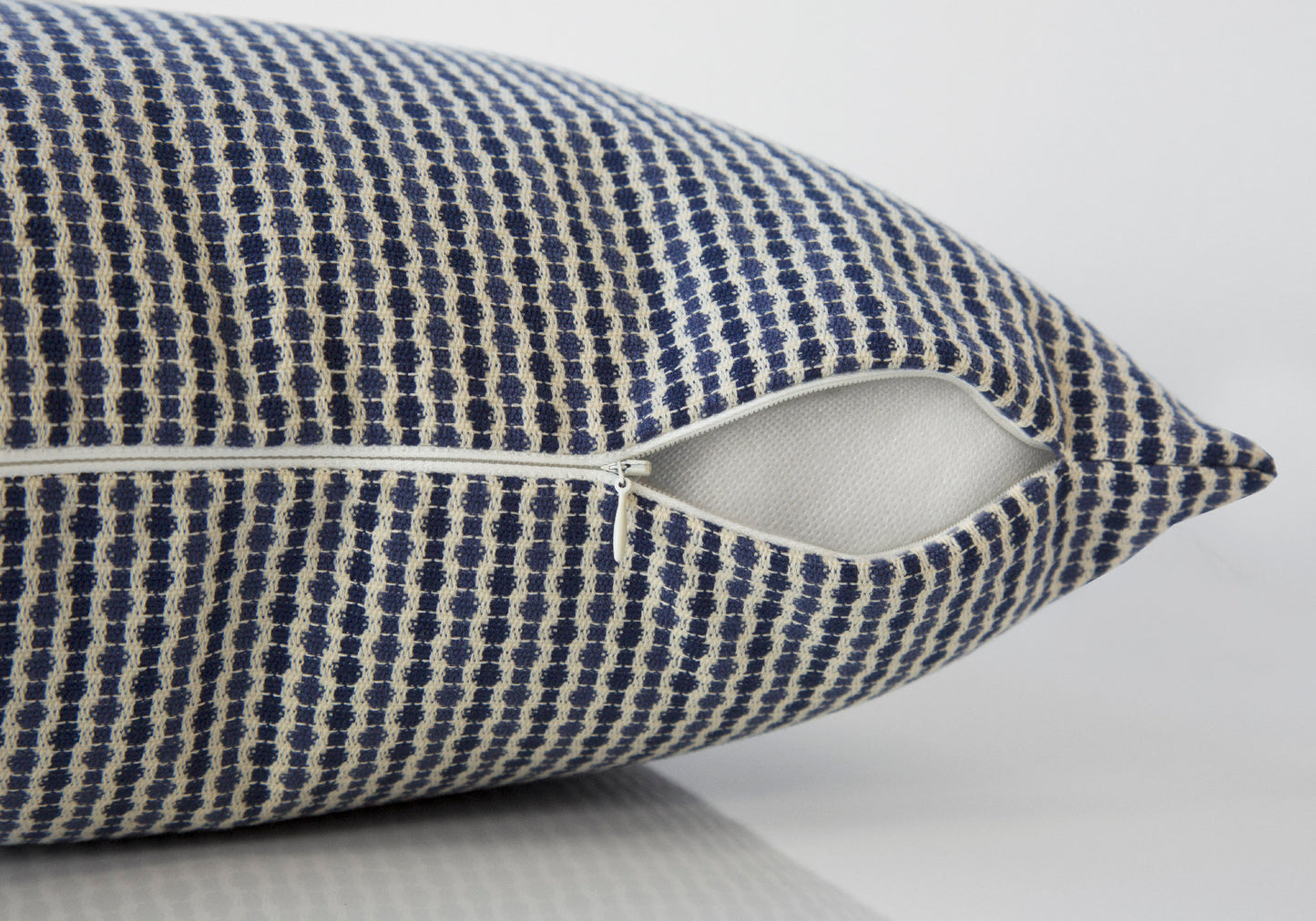 Closeup of a textured navy blue and cream throw pillow with an open zipper detail