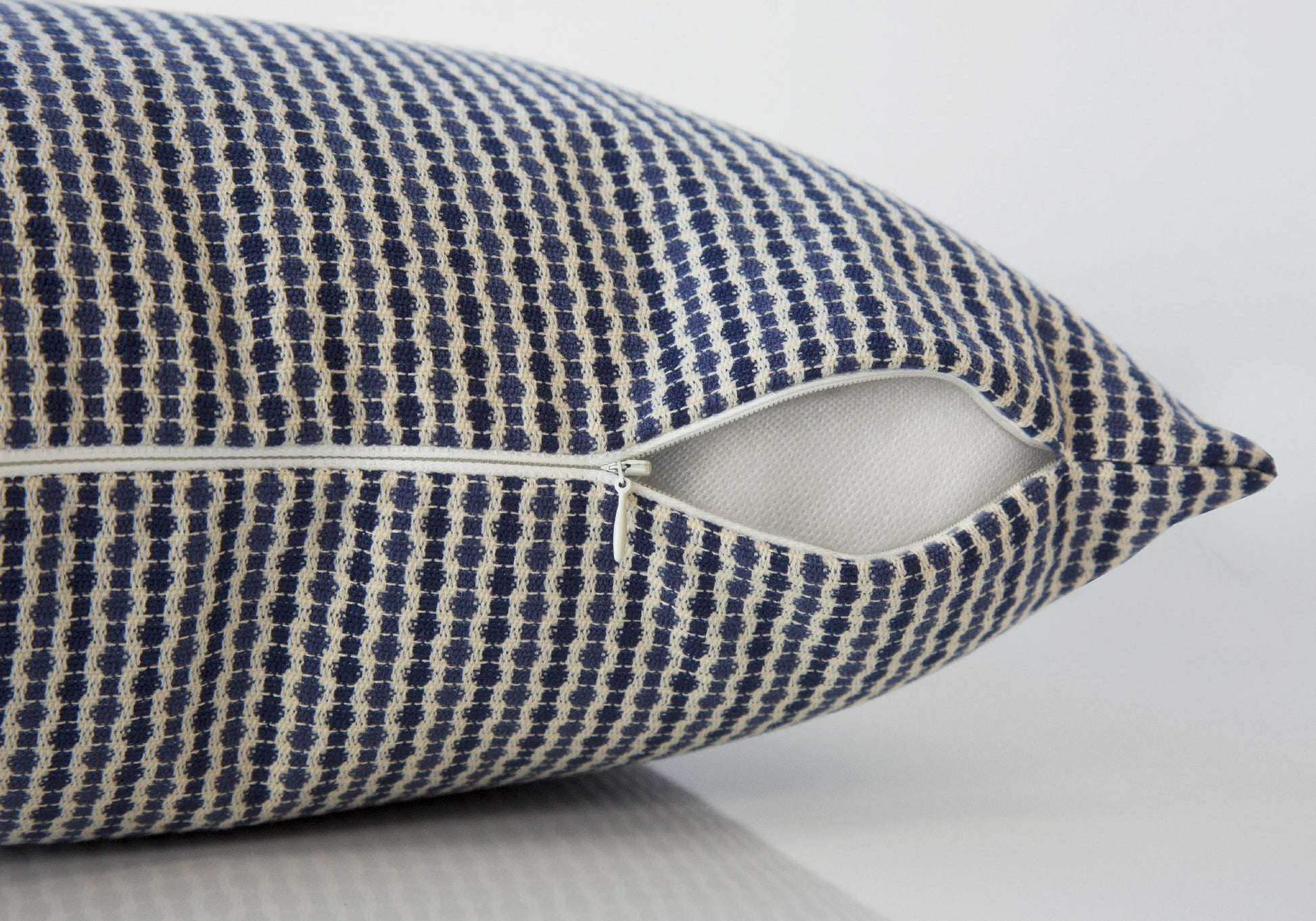 Closeup of a textured navy blue and cream throw pillow with an open zipper detail