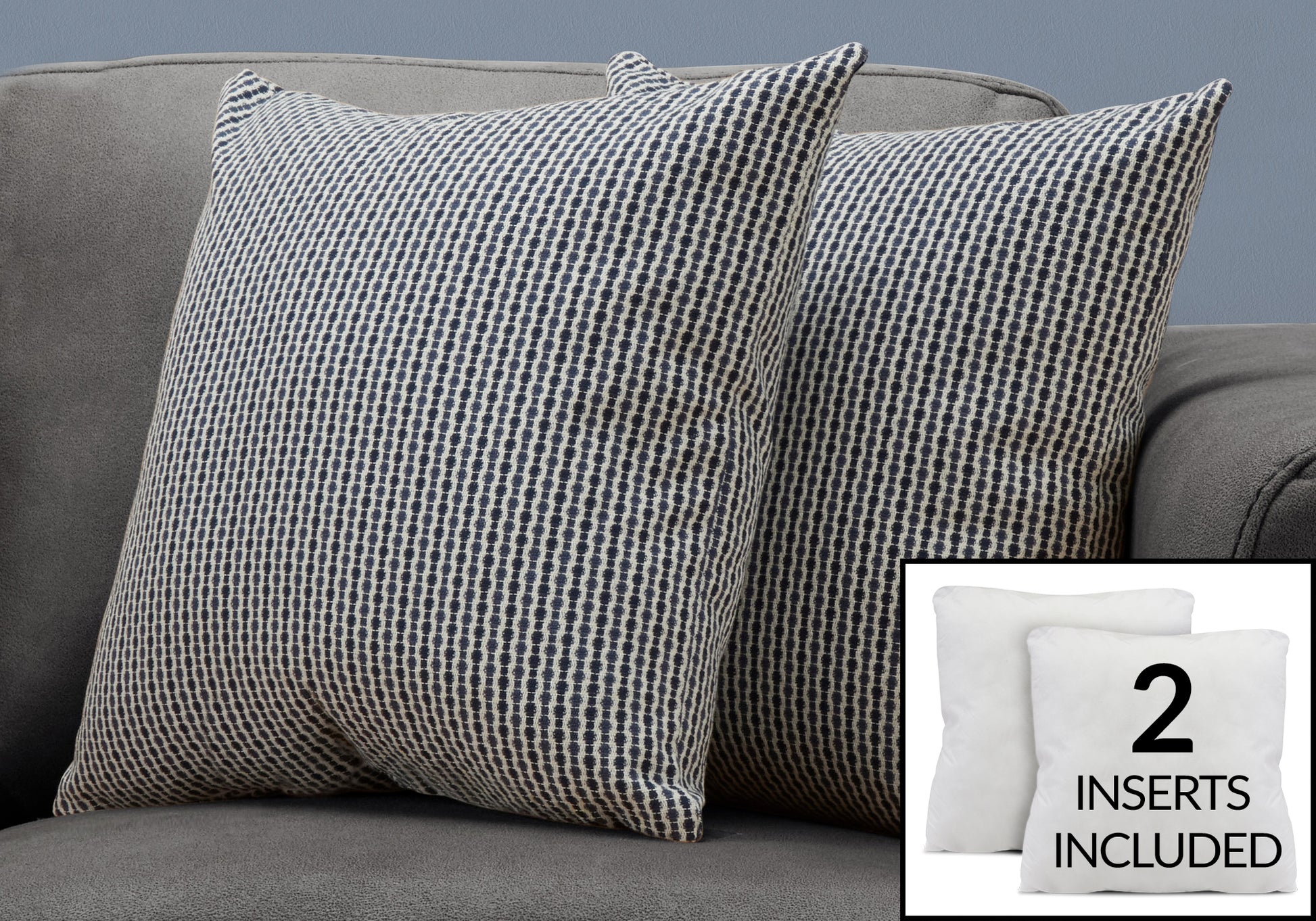 Two navy and cream geometric patterned throw pillows on a grey sofa