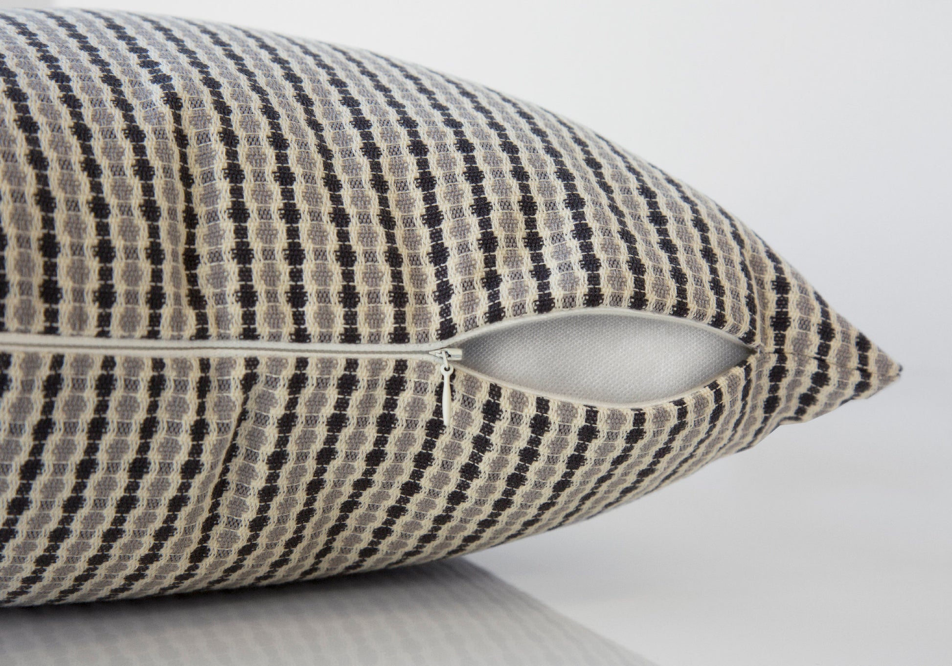 Textured throw pillow cover in gray and beige diamond pattern with visible zipper closure