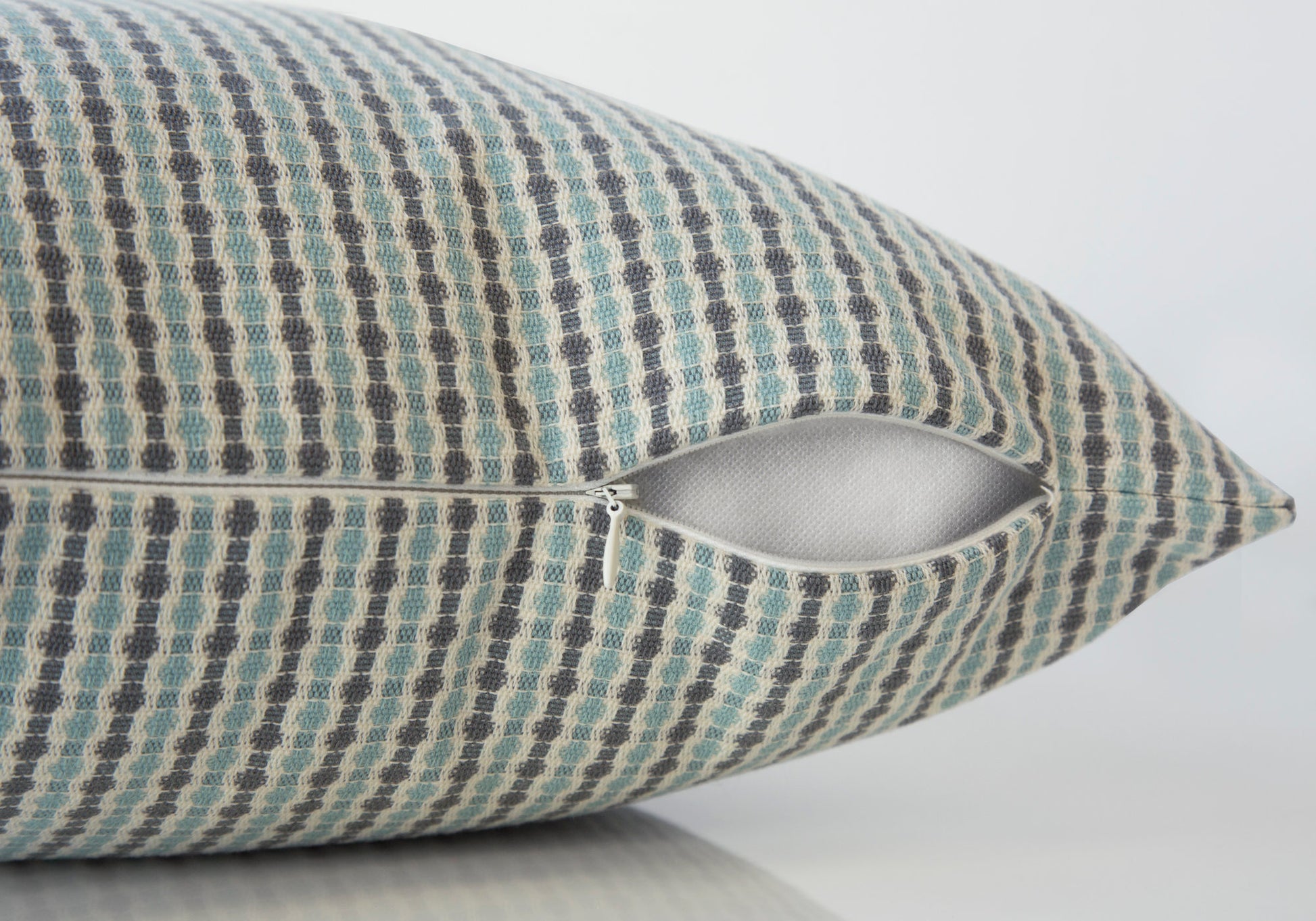 Blue and grey geometric patterned throw pillow with open zipper detail