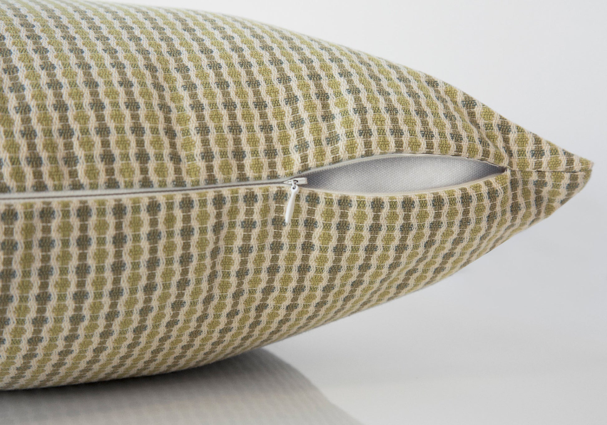 Textured olive green and beige throw pillow with geometric pattern and zipper