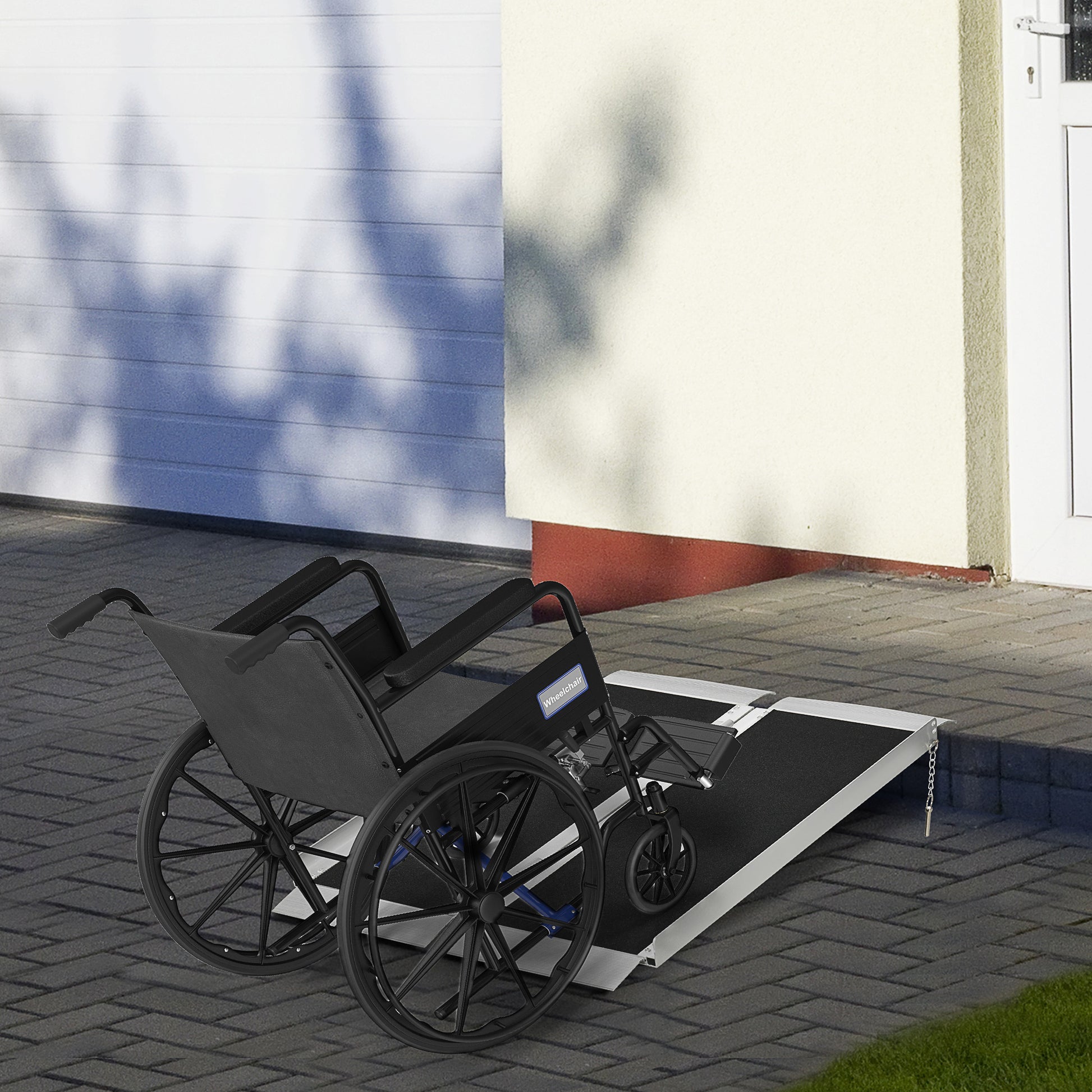 Black manual wheelchair positioned on a portable ramp for home accessibility