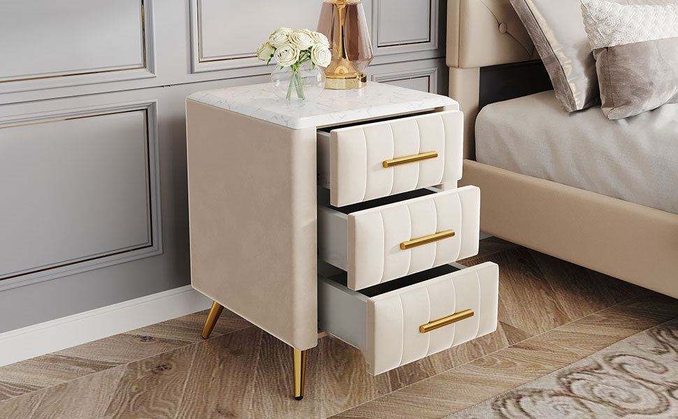 Beige velvet nightstand with marble top and three goldhandled drawers