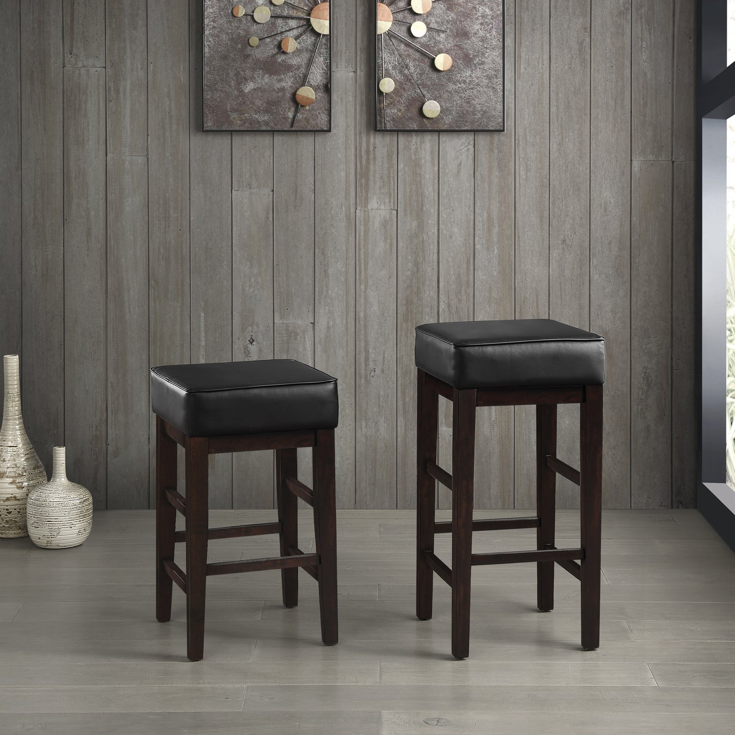Two dark brown wooden bar stools with black faux leather seats and a modern design