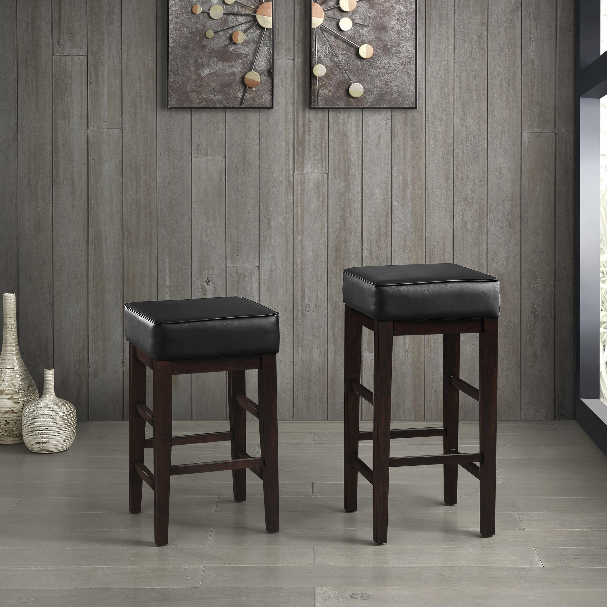 Two dark brown wooden bar stools with black faux leather seats and a modern design