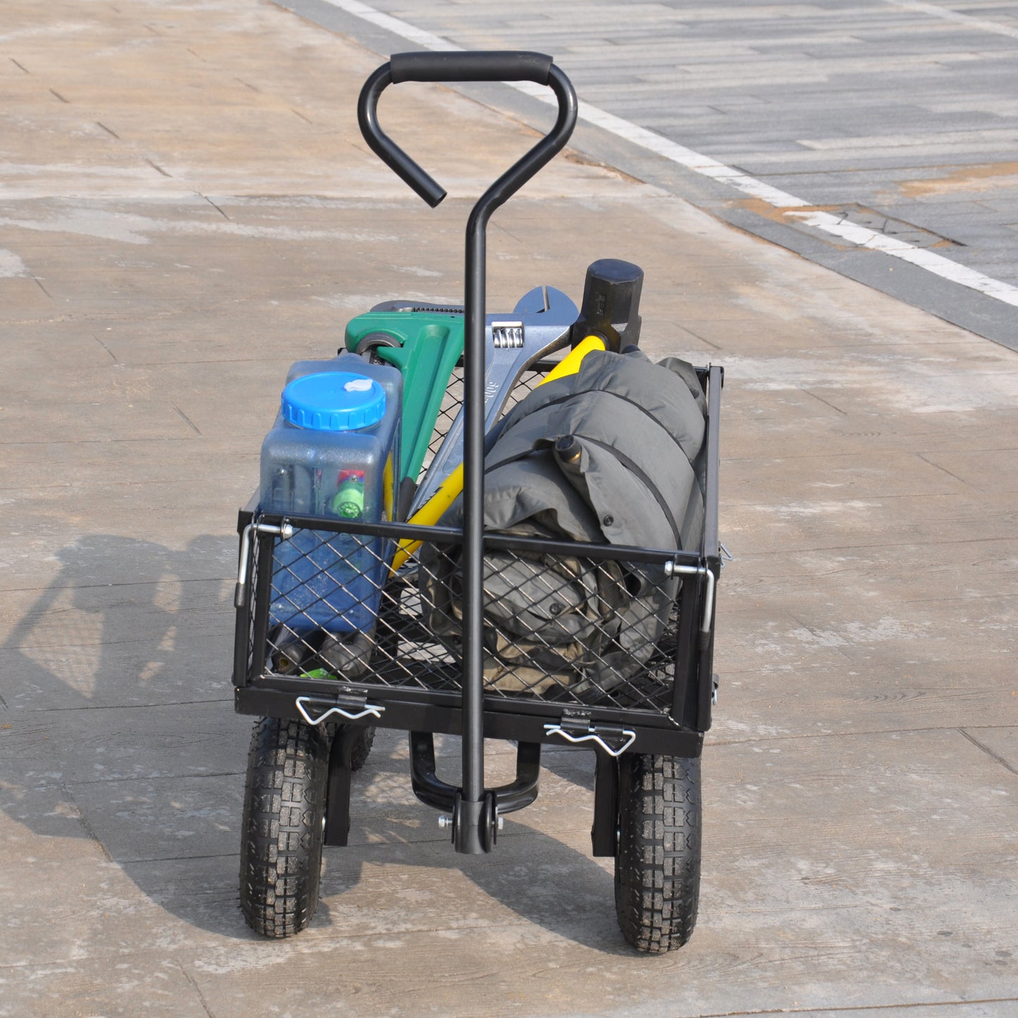 Black metal garden cart loaded with tools a blue water jug and a folded grey tarp for hauling