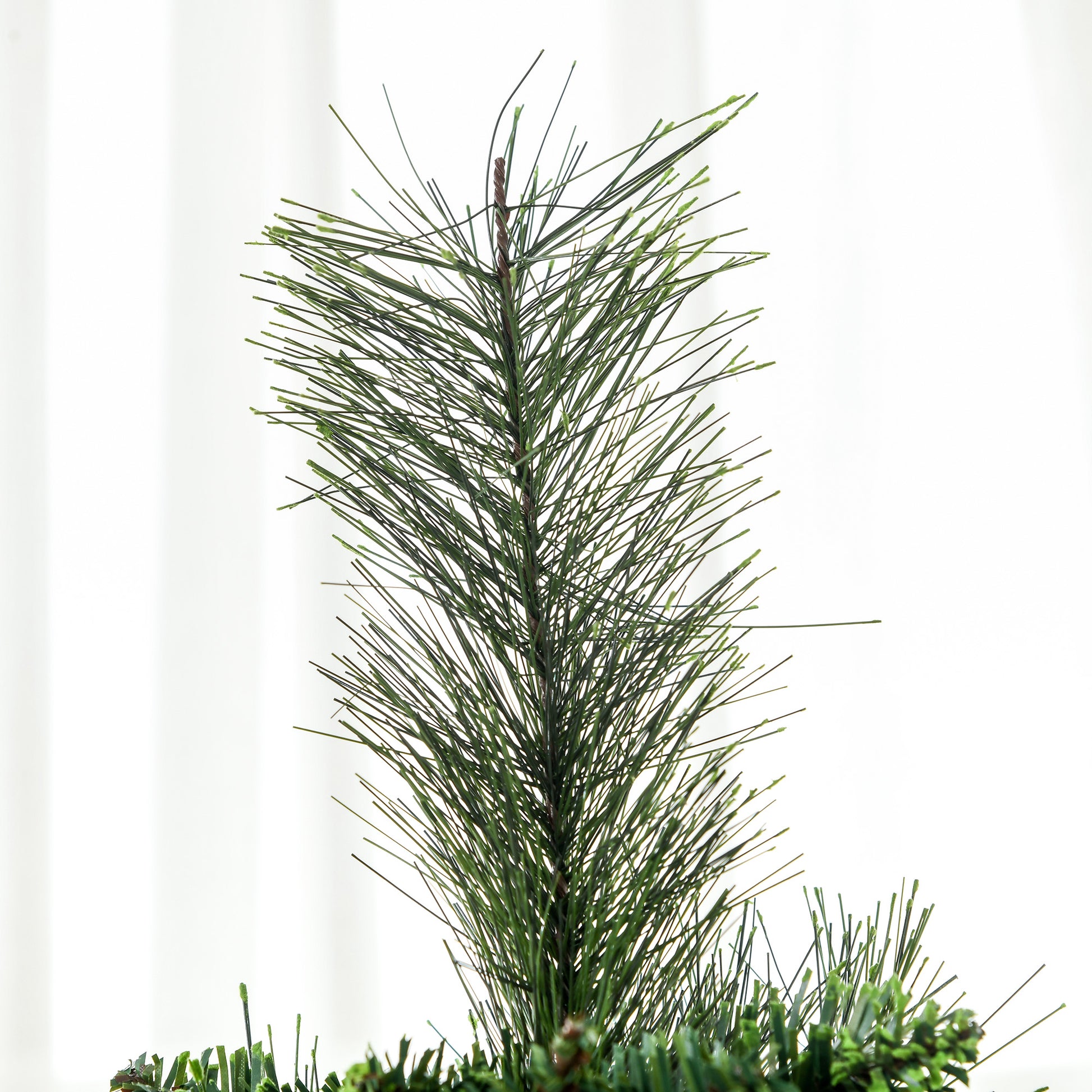 Closeup of a realistic artificial Christmas tree with dense green pine needles on a white background