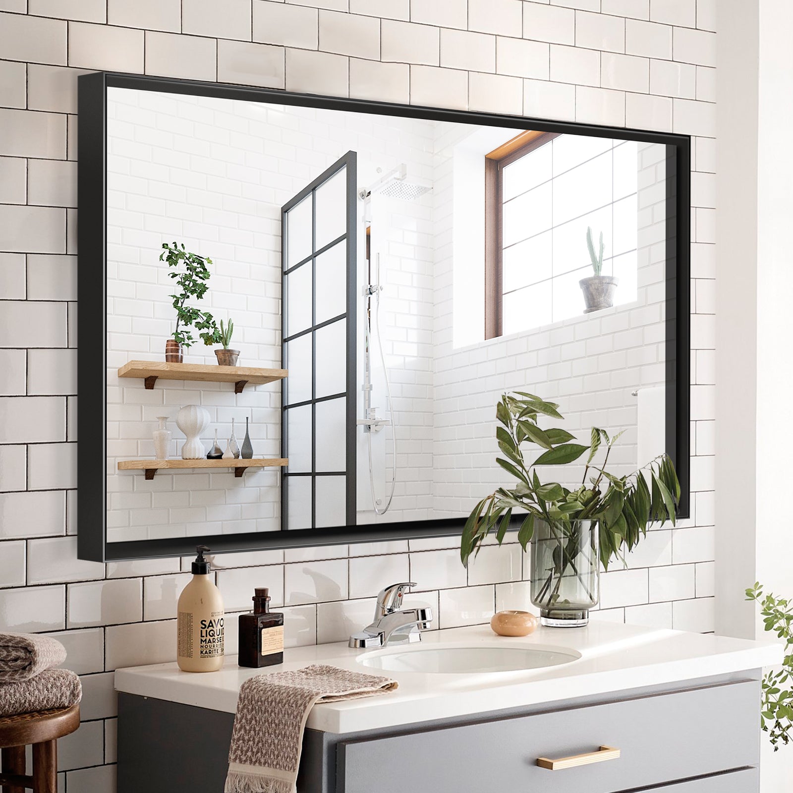Modern black framed bathroom mirror with clean lines reflecting a stylish vanity